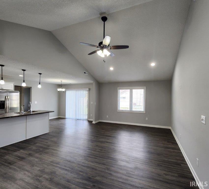 Unfurnished living room featuring ceiling fan and dark wood-type flooring