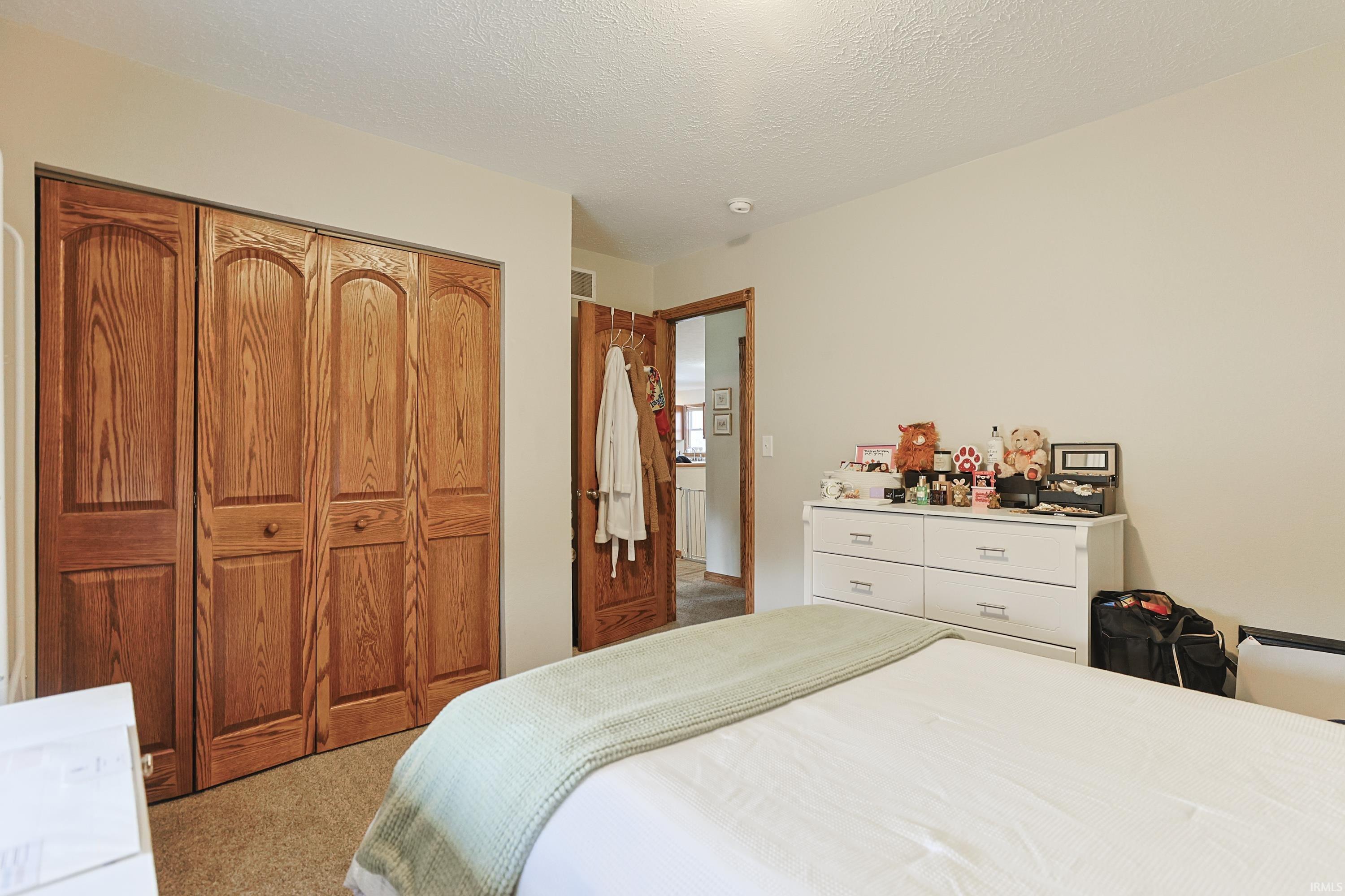 Bedroom featuring light carpet, a closet, and a textured ceiling