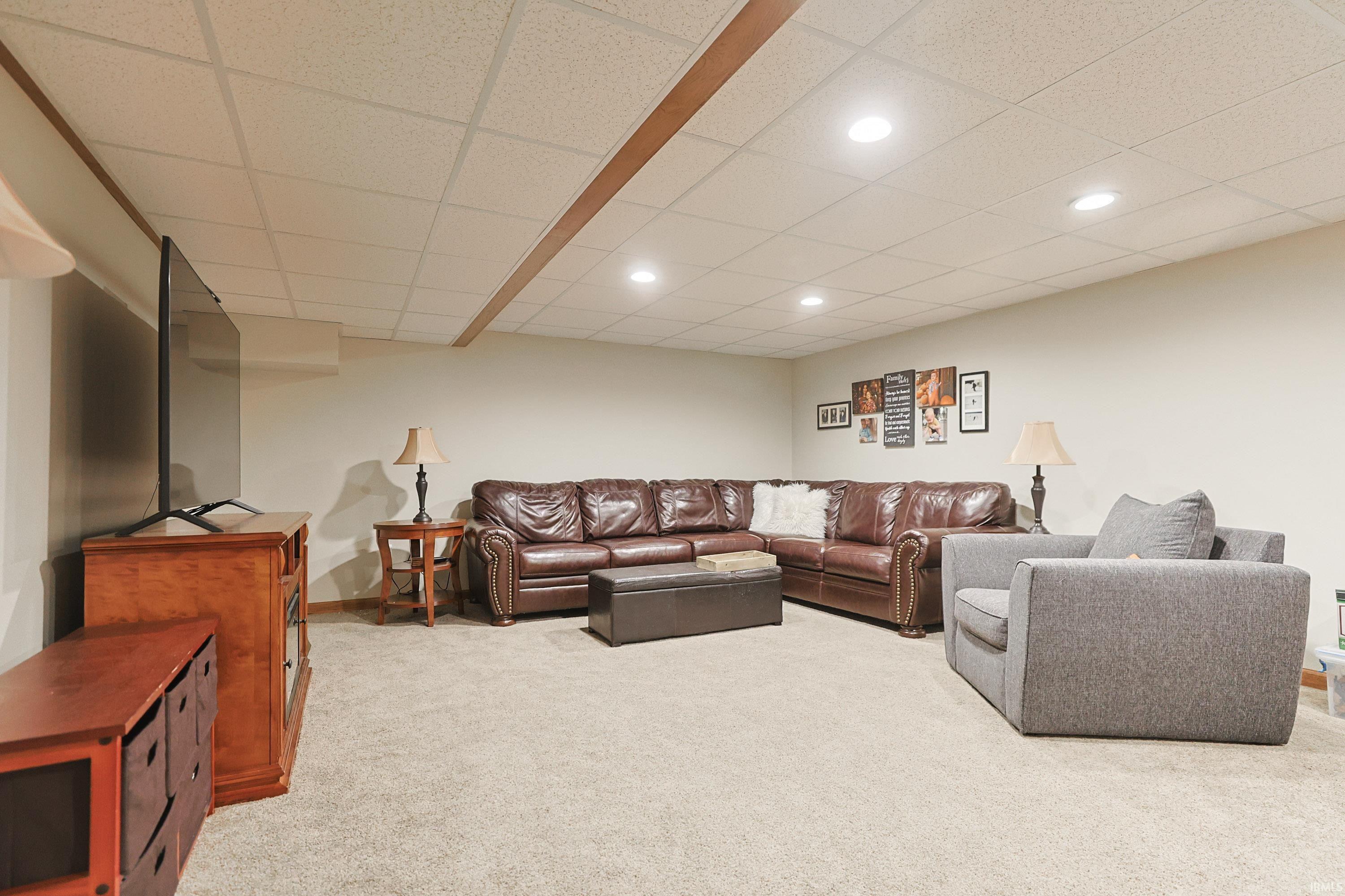 Living room with a paneled ceiling, light colored carpet, and recessed lighting