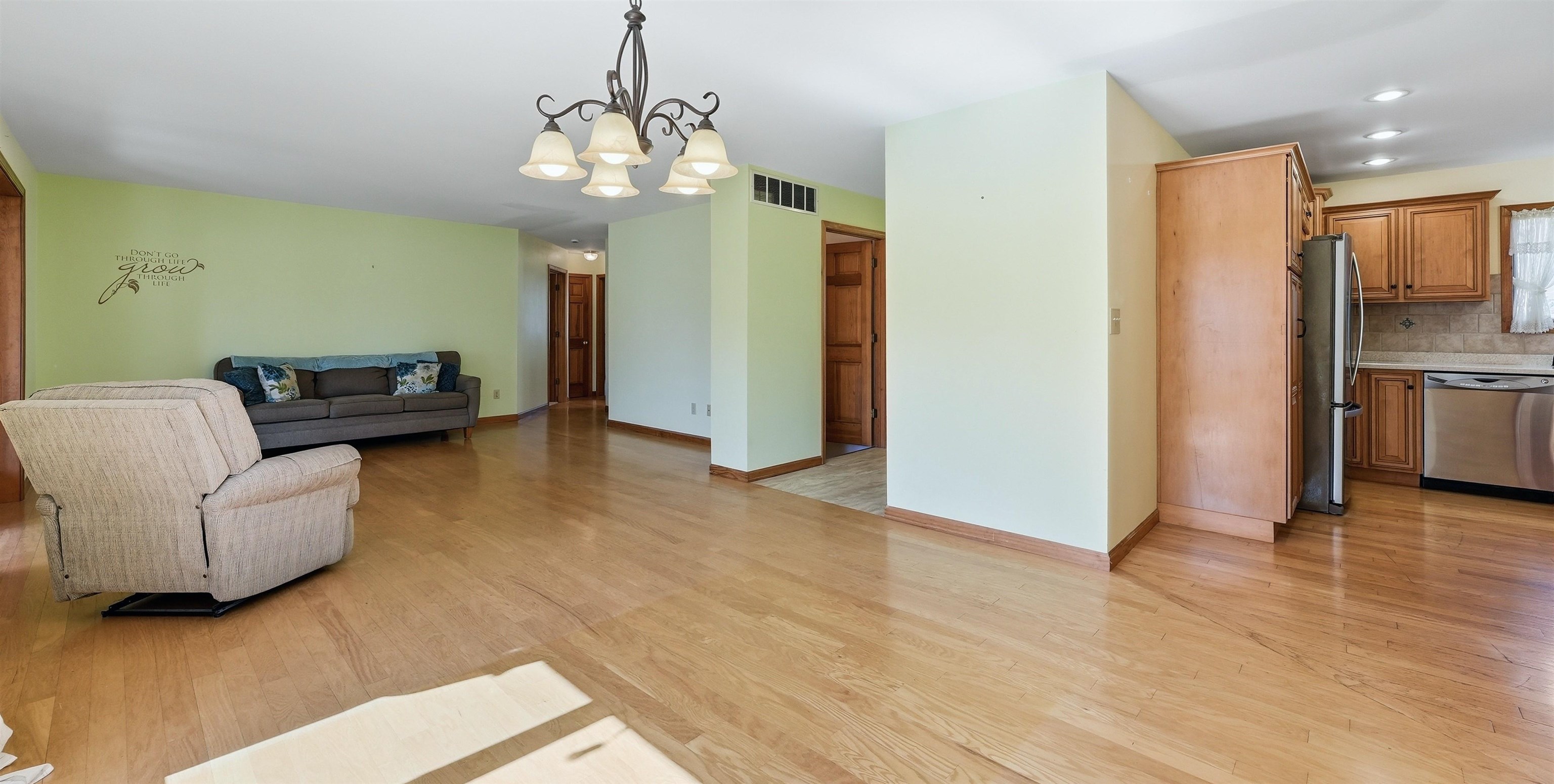 Living area with light wood finished floors and hanging lights