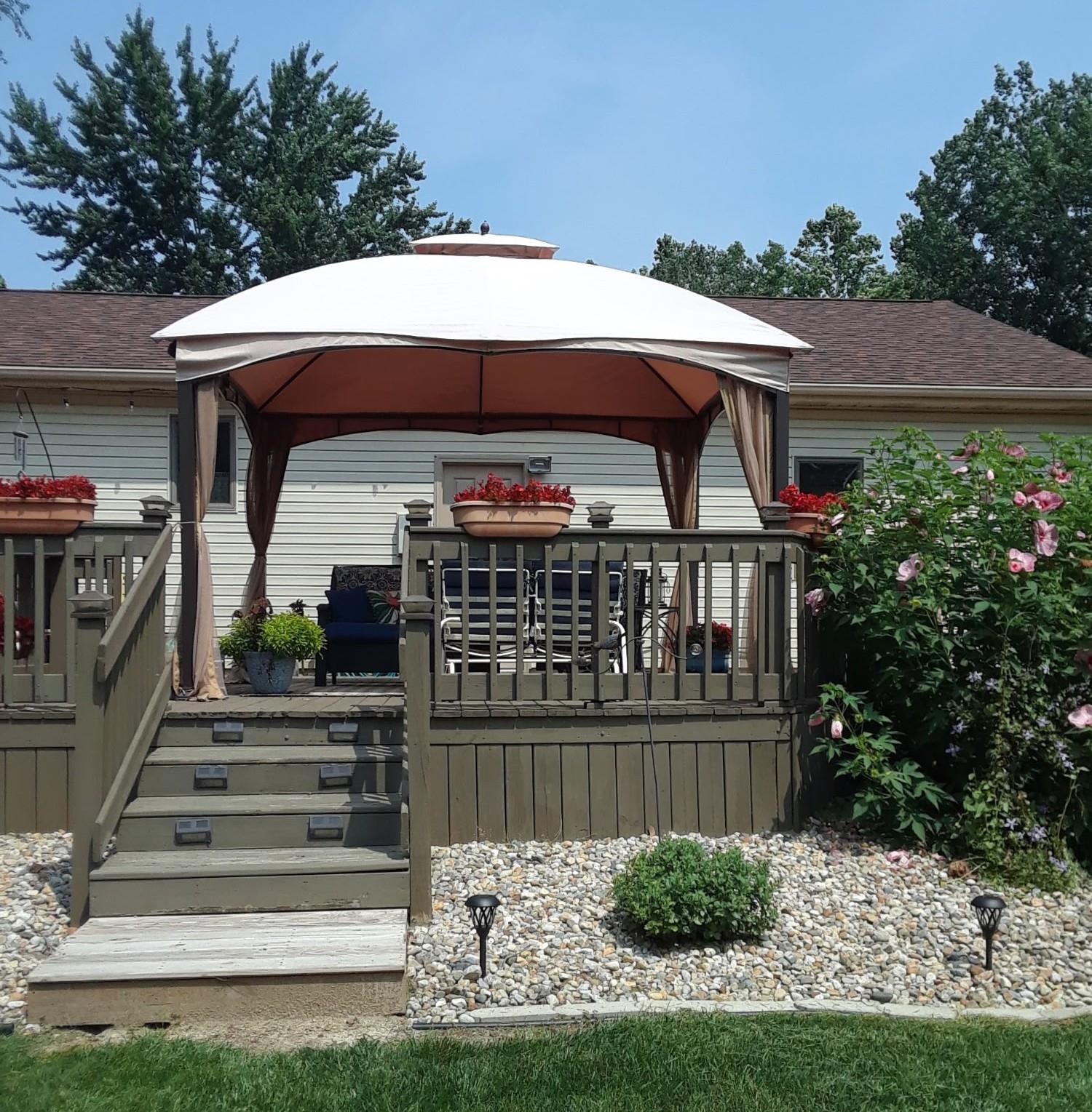 Rear view of the property featuring a gazebo, a deck, and days of sunshine