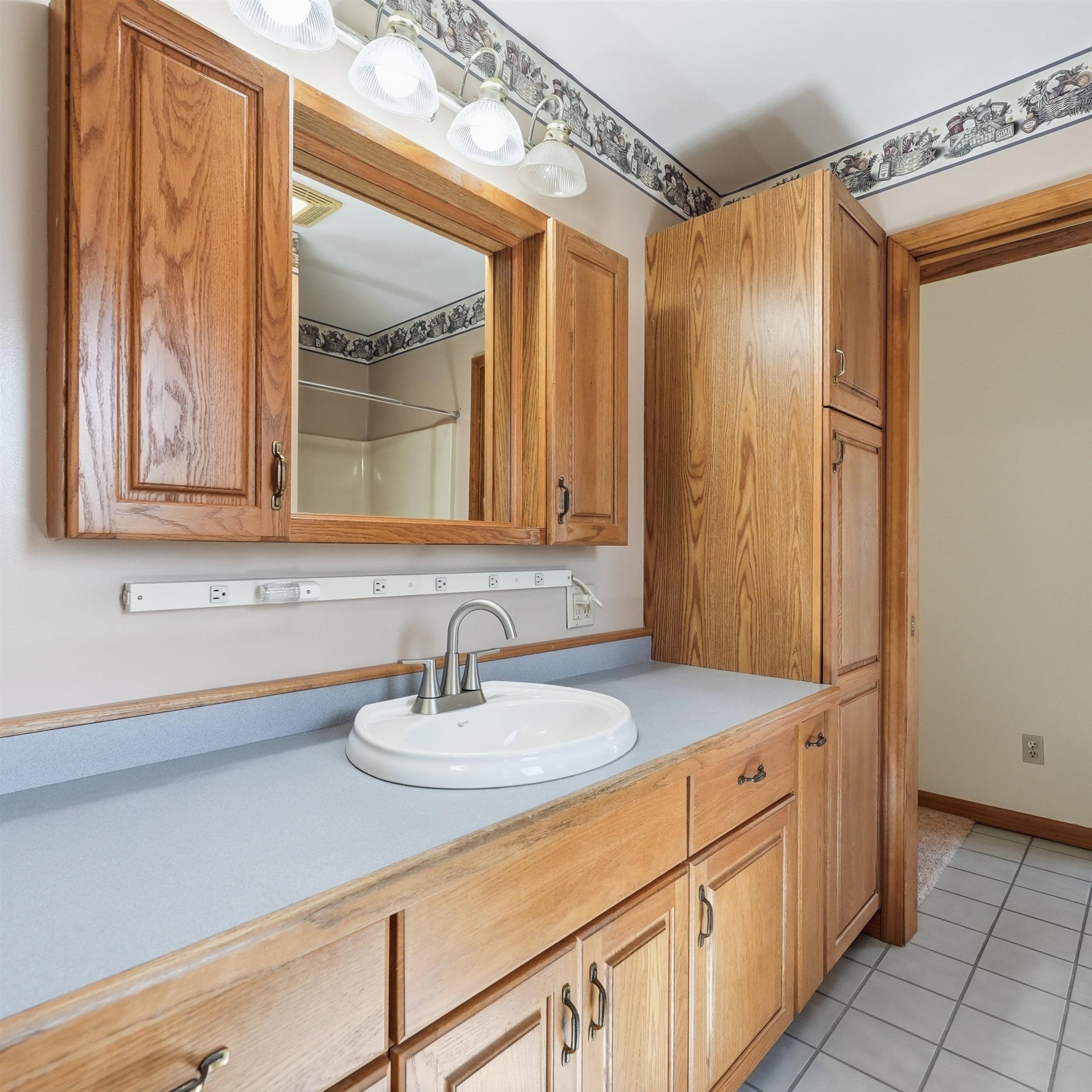Full bathroom featuring vanity, light tile patterned floors, and a shower