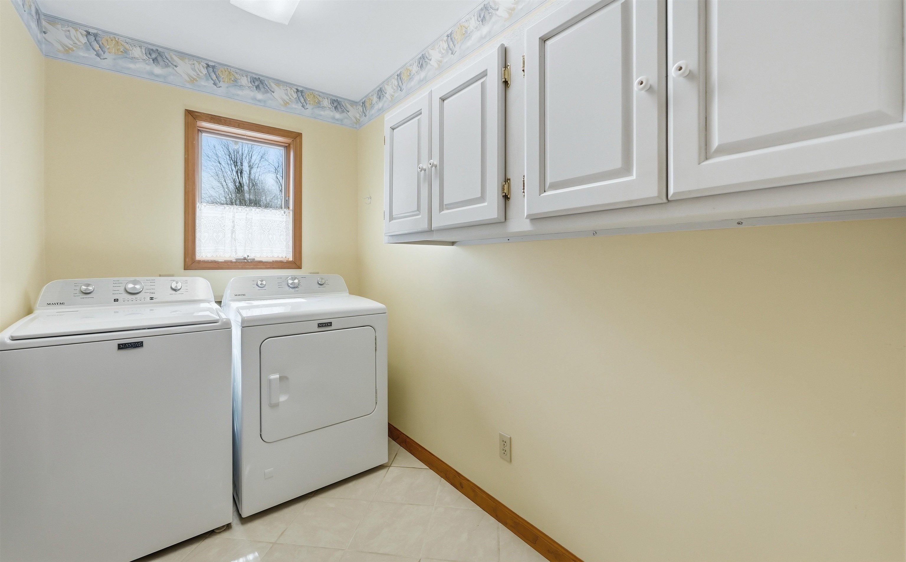 Laundry room featuring separate washer and dryer, cabinet space, and light tile patterned floors