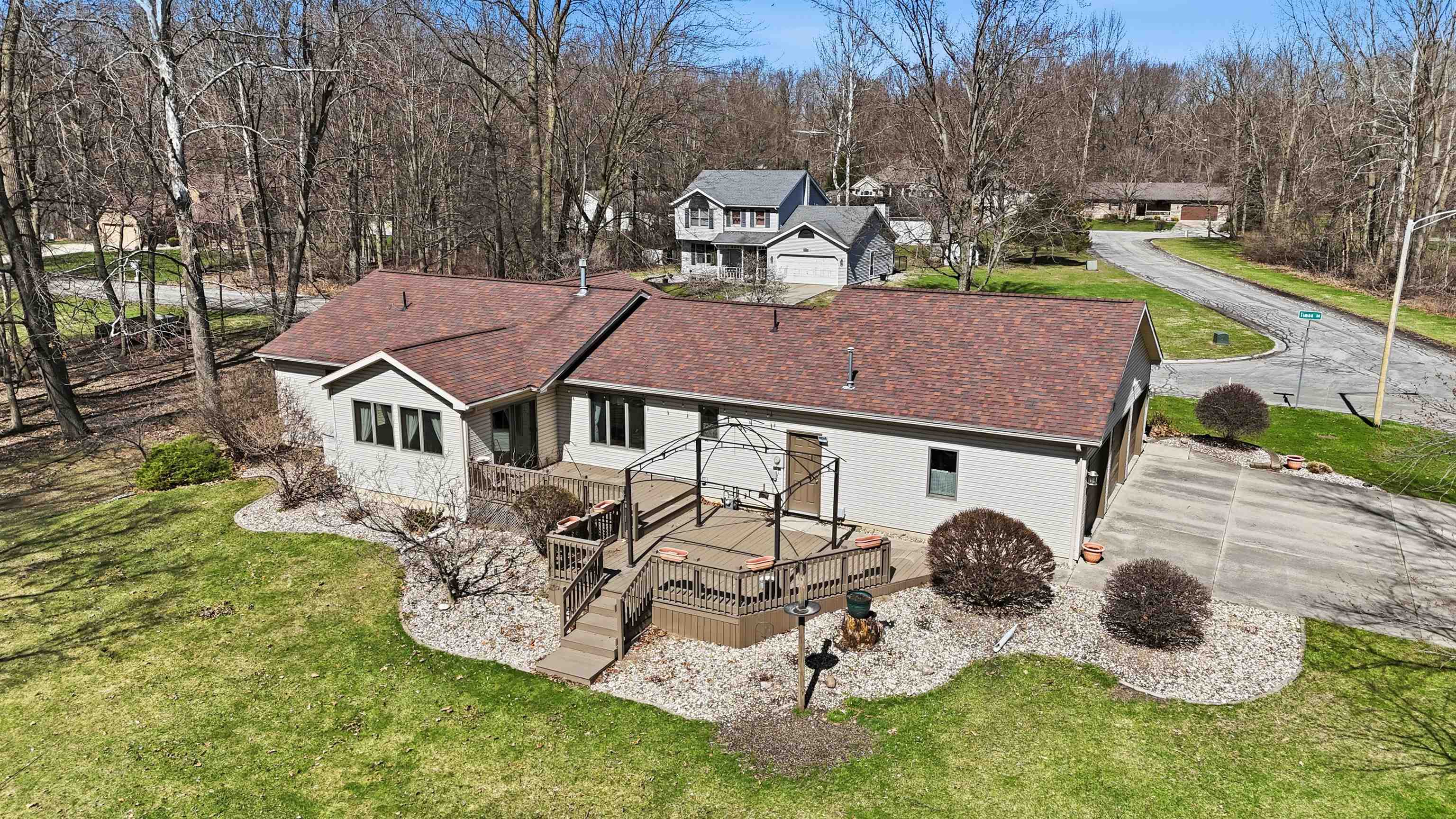 Rear view of property featuring a wooden deck, a shingled roof, a yard, and view of scattered trees