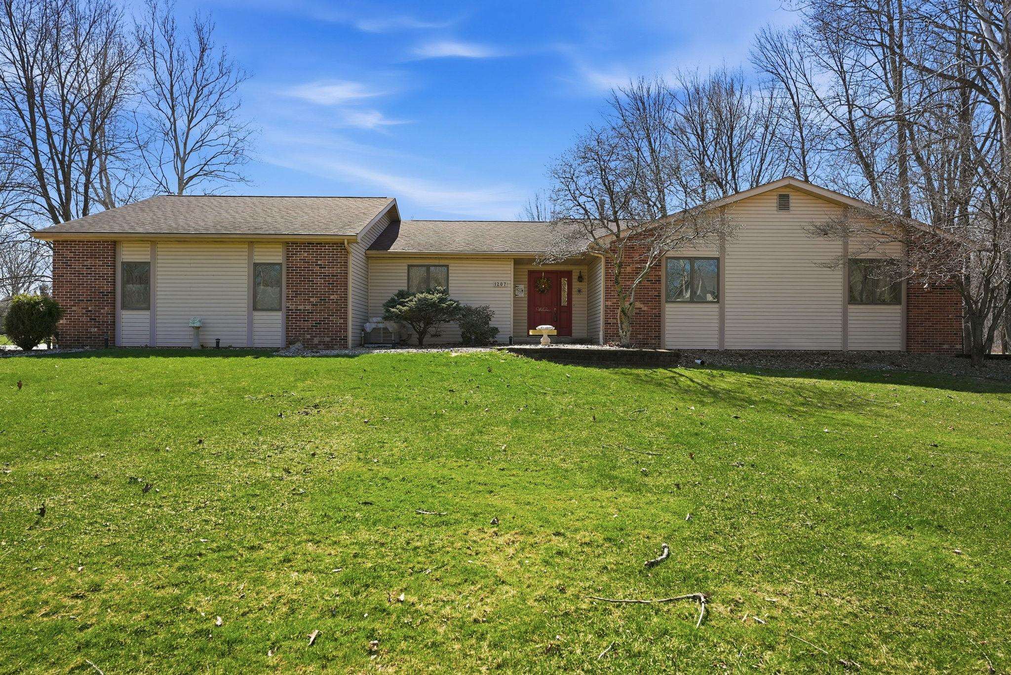 Single story home with brick siding, a front lawn, and roof with shingles