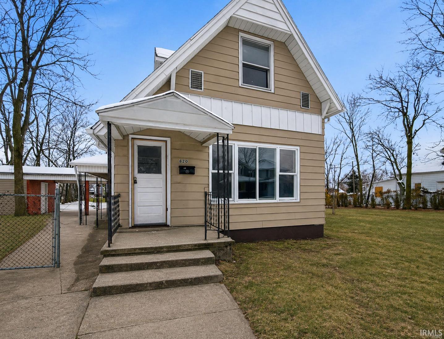 Gabled residence featuring tan siding and white trim accents