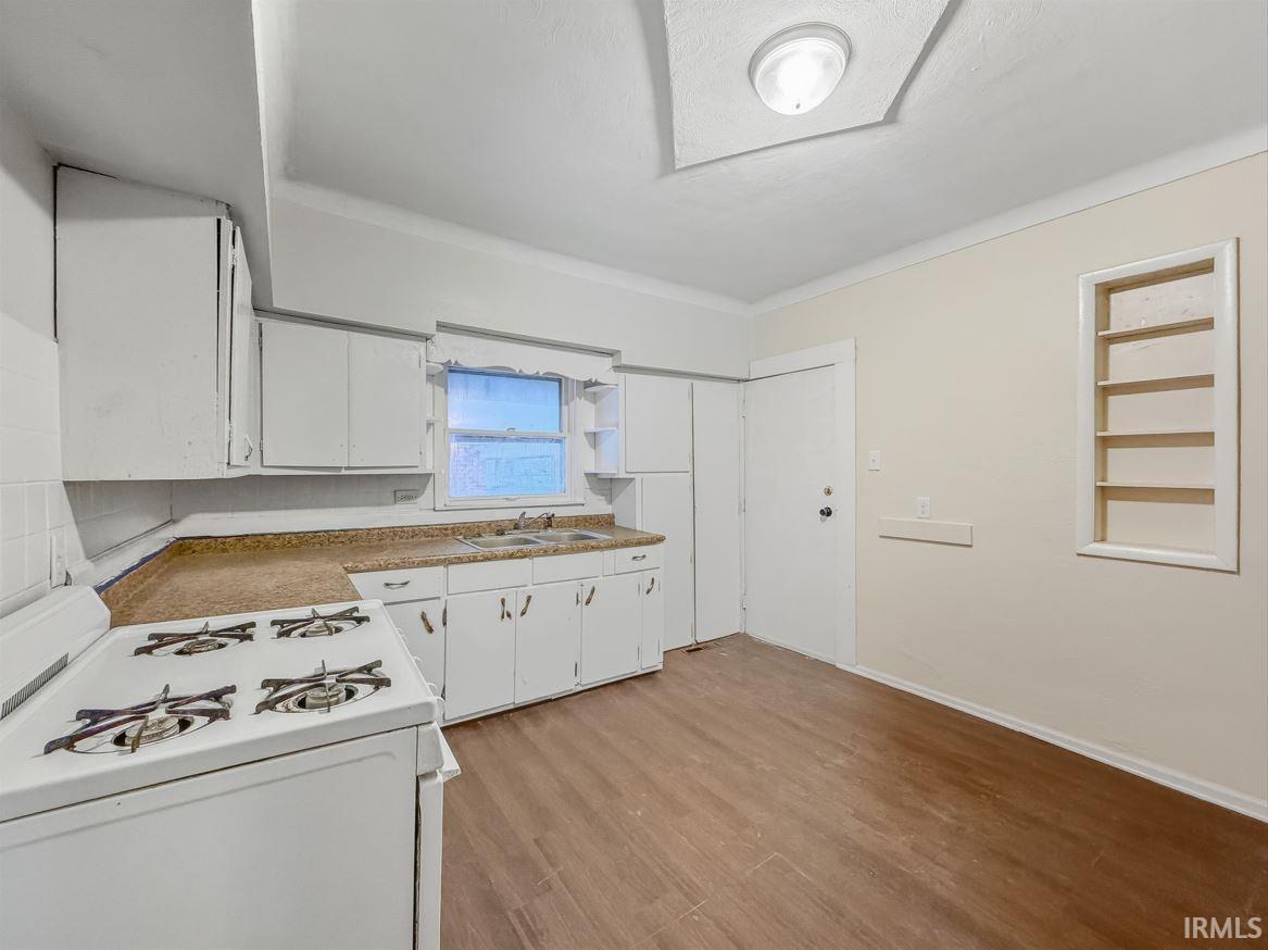 Kitchen featuring white range with gas cooktop, white cabinetry, built in features, light countertops, and light wood-style floors
