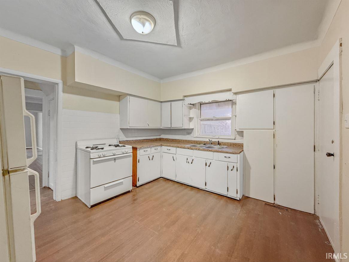 Kitchen with white appliances, white cabinetry, light wood-type flooring, a textured ceiling, and open shelves