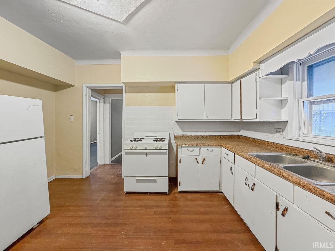Kitchen featuring white appliances, white cabinetry, dark wood-type flooring, open shelves, and light countertops