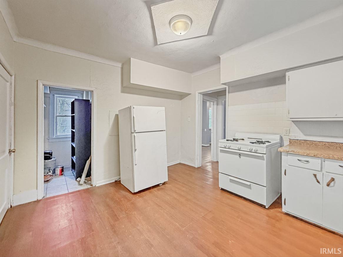 Kitchen featuring white appliances, light countertops, white cabinetry, light wood finished floors, and a textured ceiling