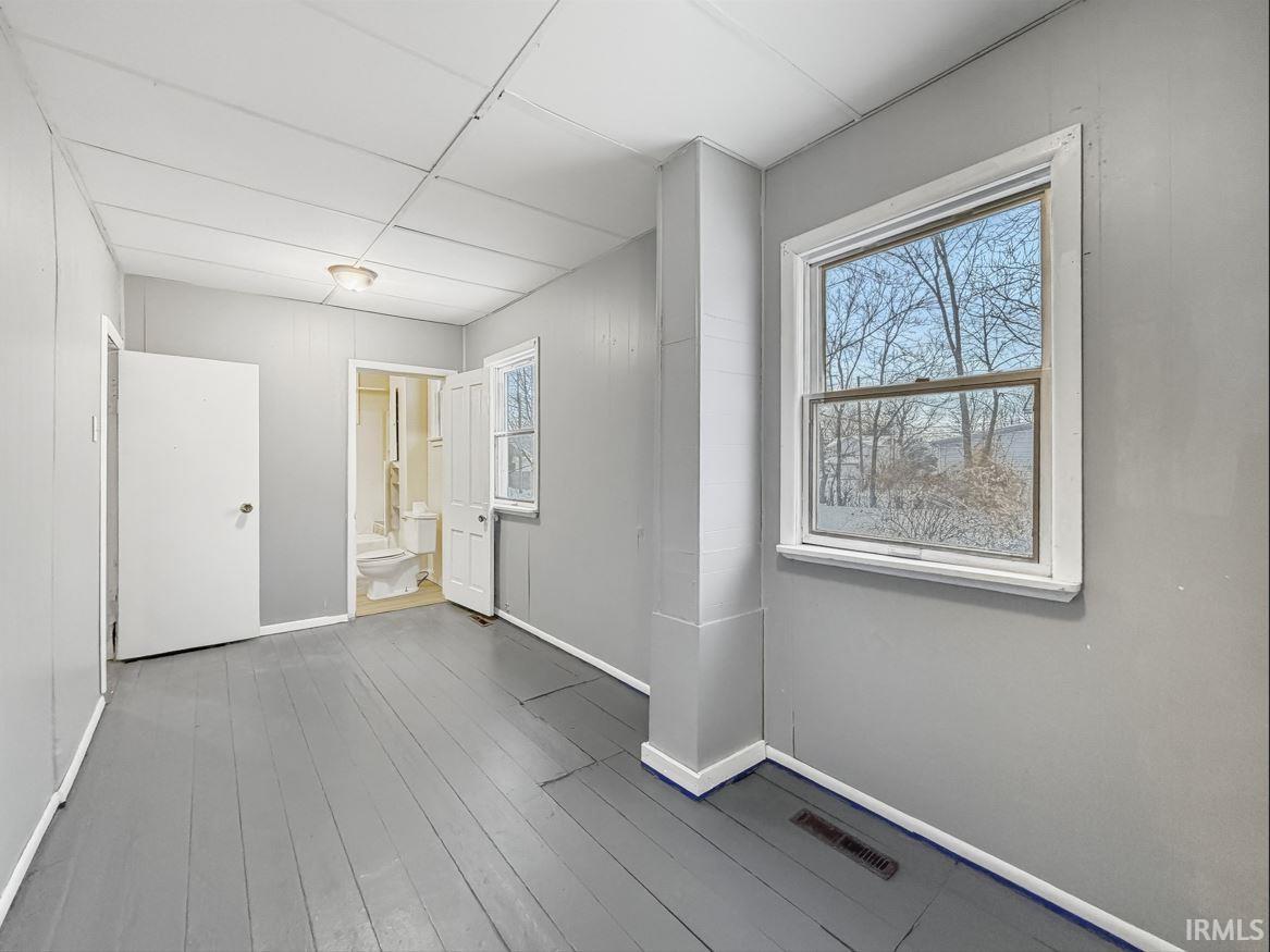Empty room featuring healthy amount of natural light and dark wood-type flooring