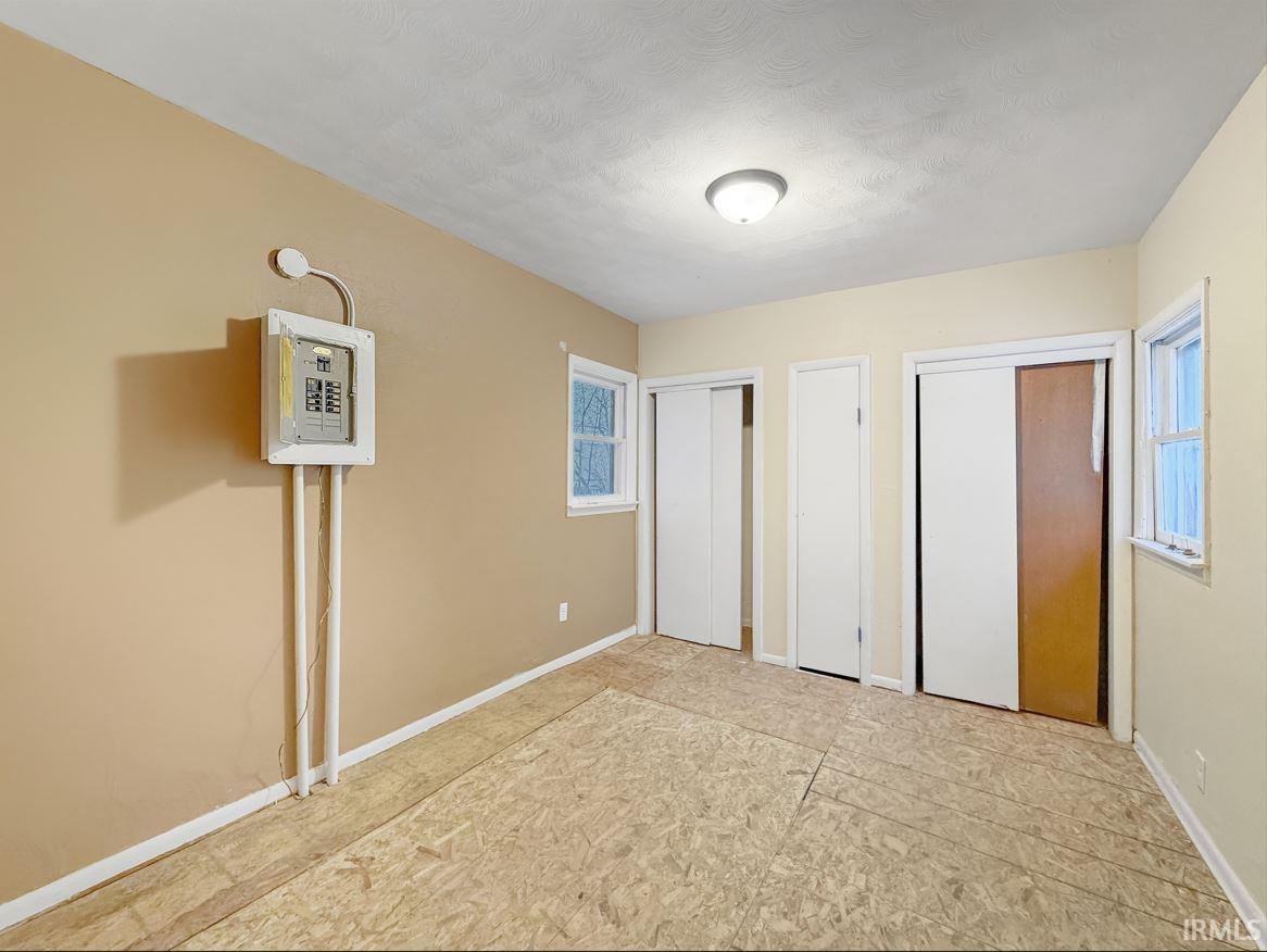 Unfurnished bedroom with two closets and baseboards