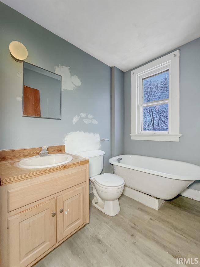 Full bath featuring light wood finished floors, vanity, and a freestanding tub