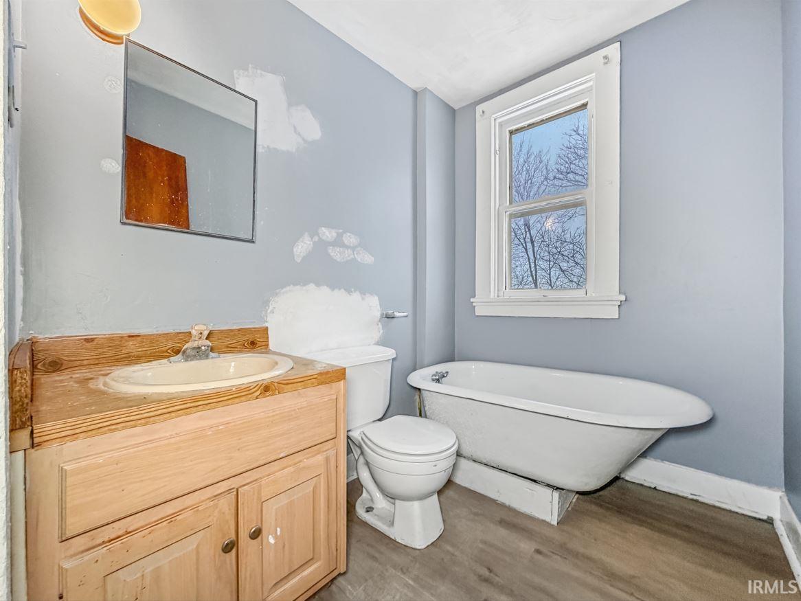 Full bath with vanity, wood finished floors, and a freestanding tub