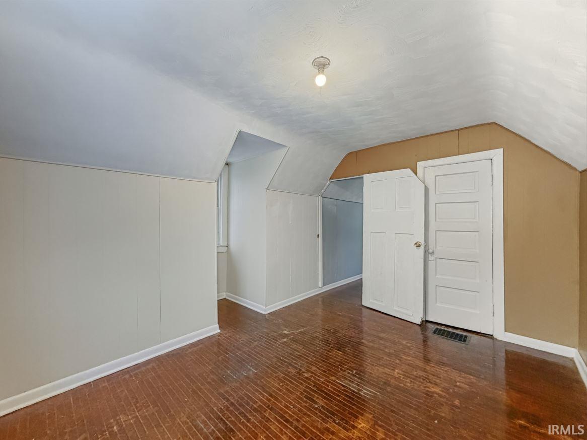 Bonus room featuring dark wood-style flooring and vaulted ceiling