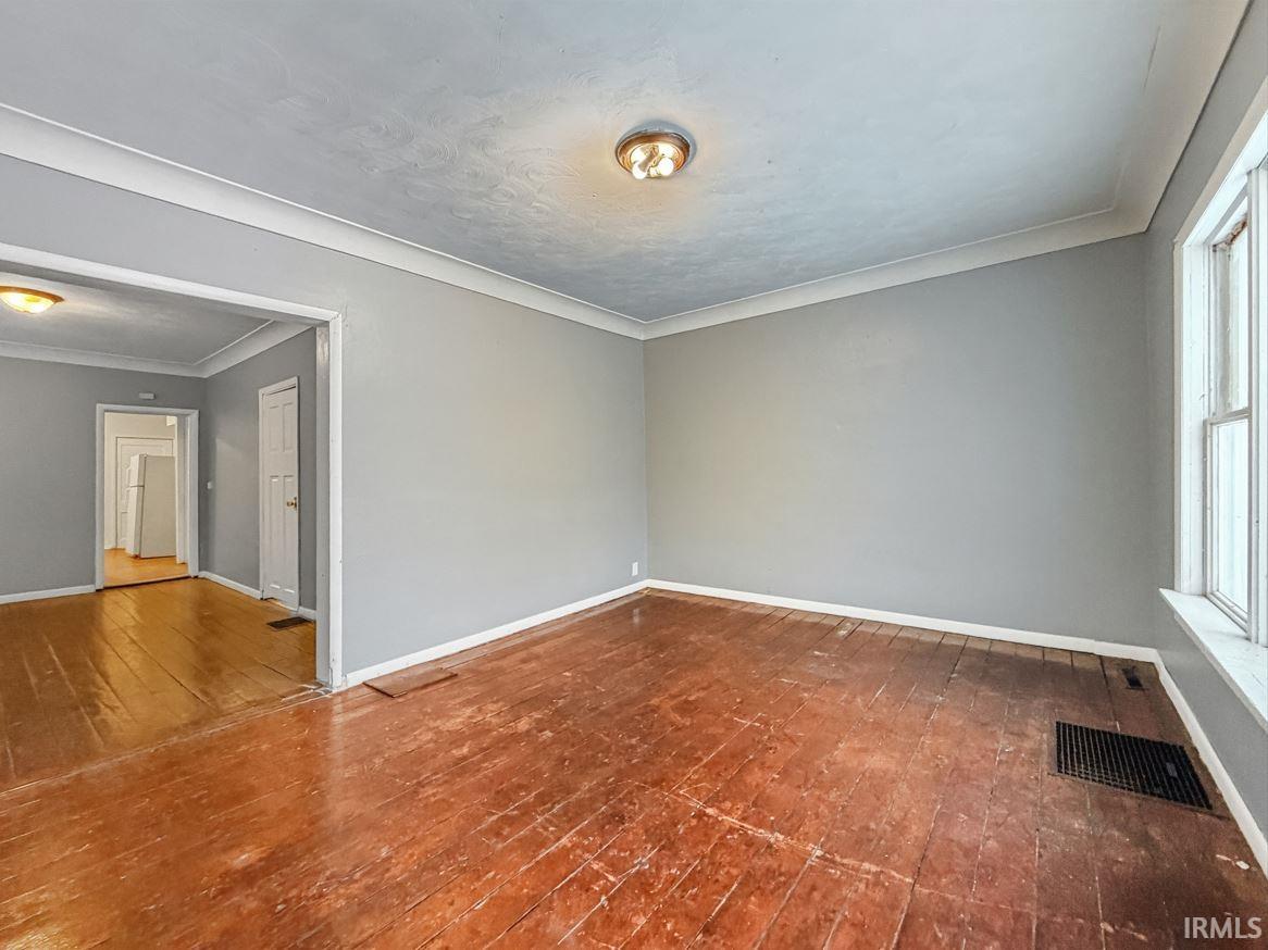 Unfurnished room with ornamental molding and dark wood finished floors