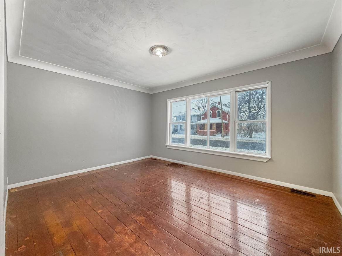 Spare room with dark wood finished floors and ornamental molding