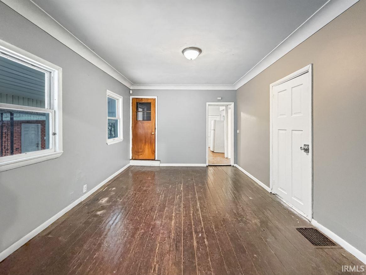 Foyer featuring dark wood-style floors and crown molding
