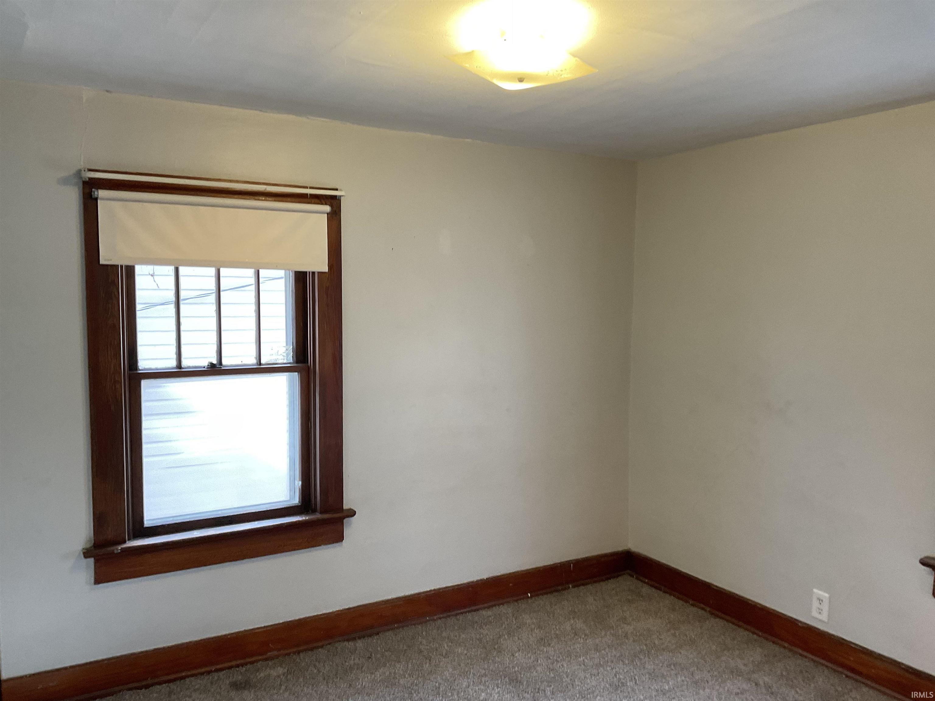 Empty room with baseboards and light colored carpet