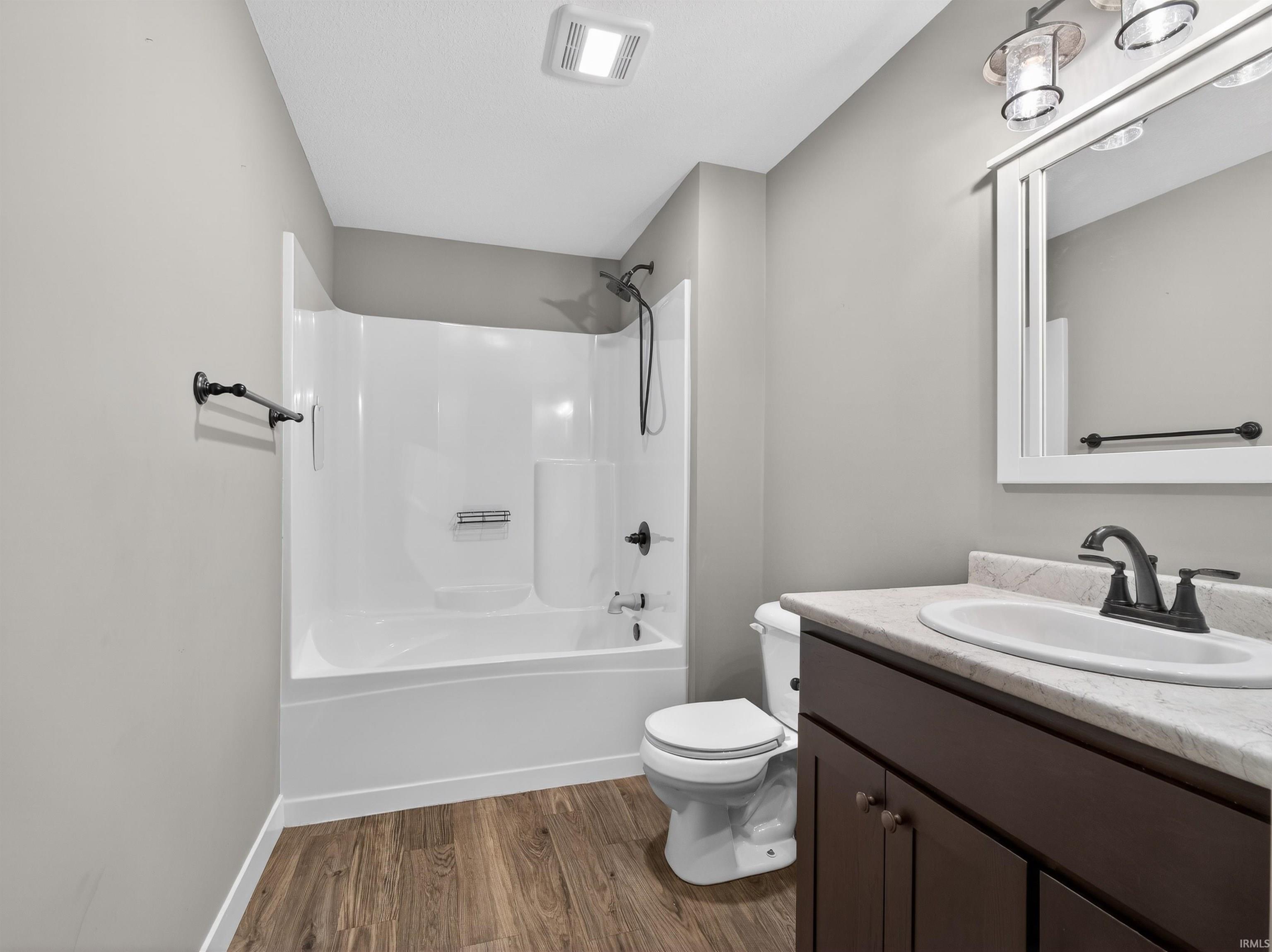Full bathroom with vanity, dark wood-type flooring, and washtub / shower combination