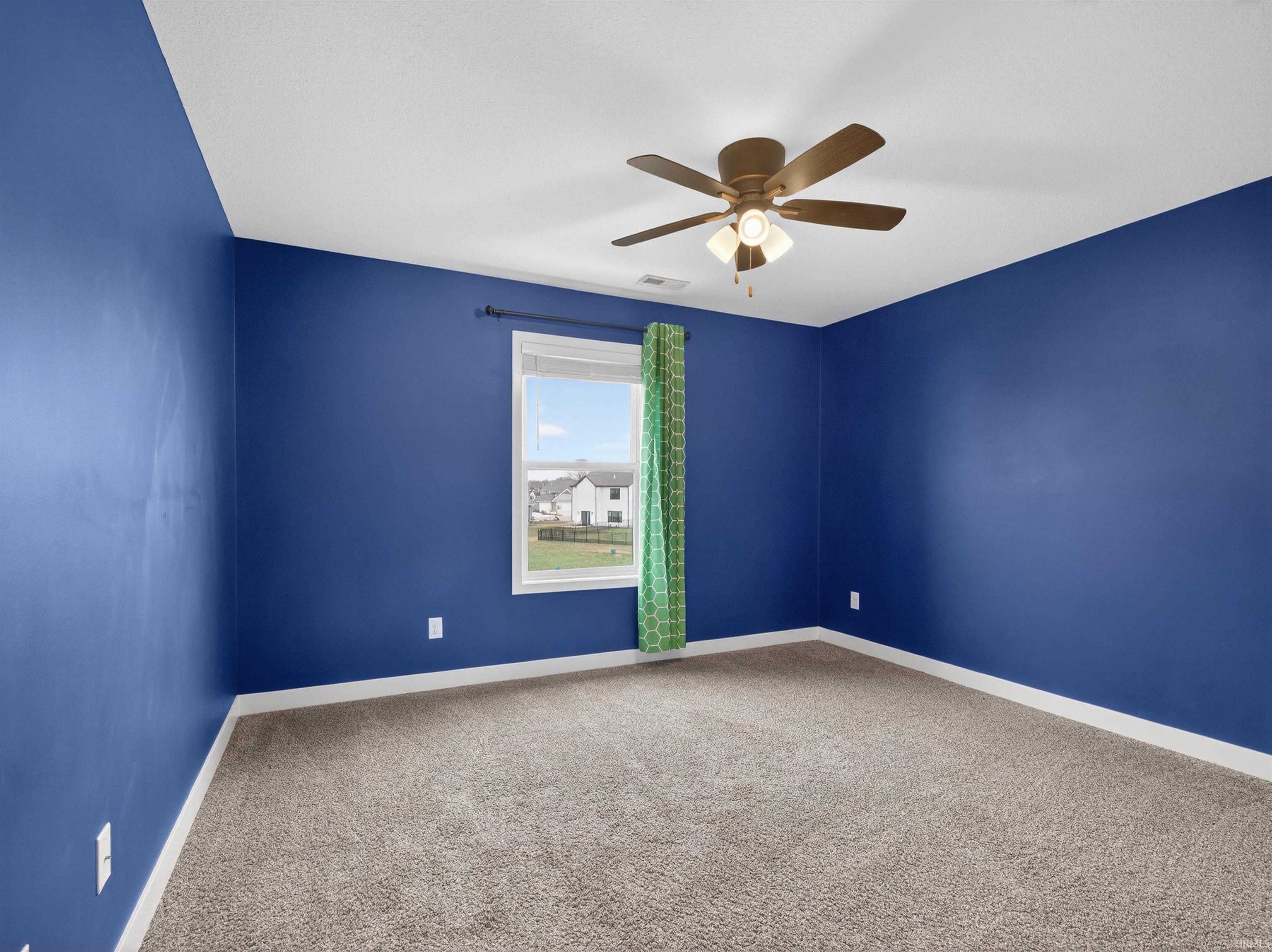 Empty room featuring light colored carpet and ceiling fan