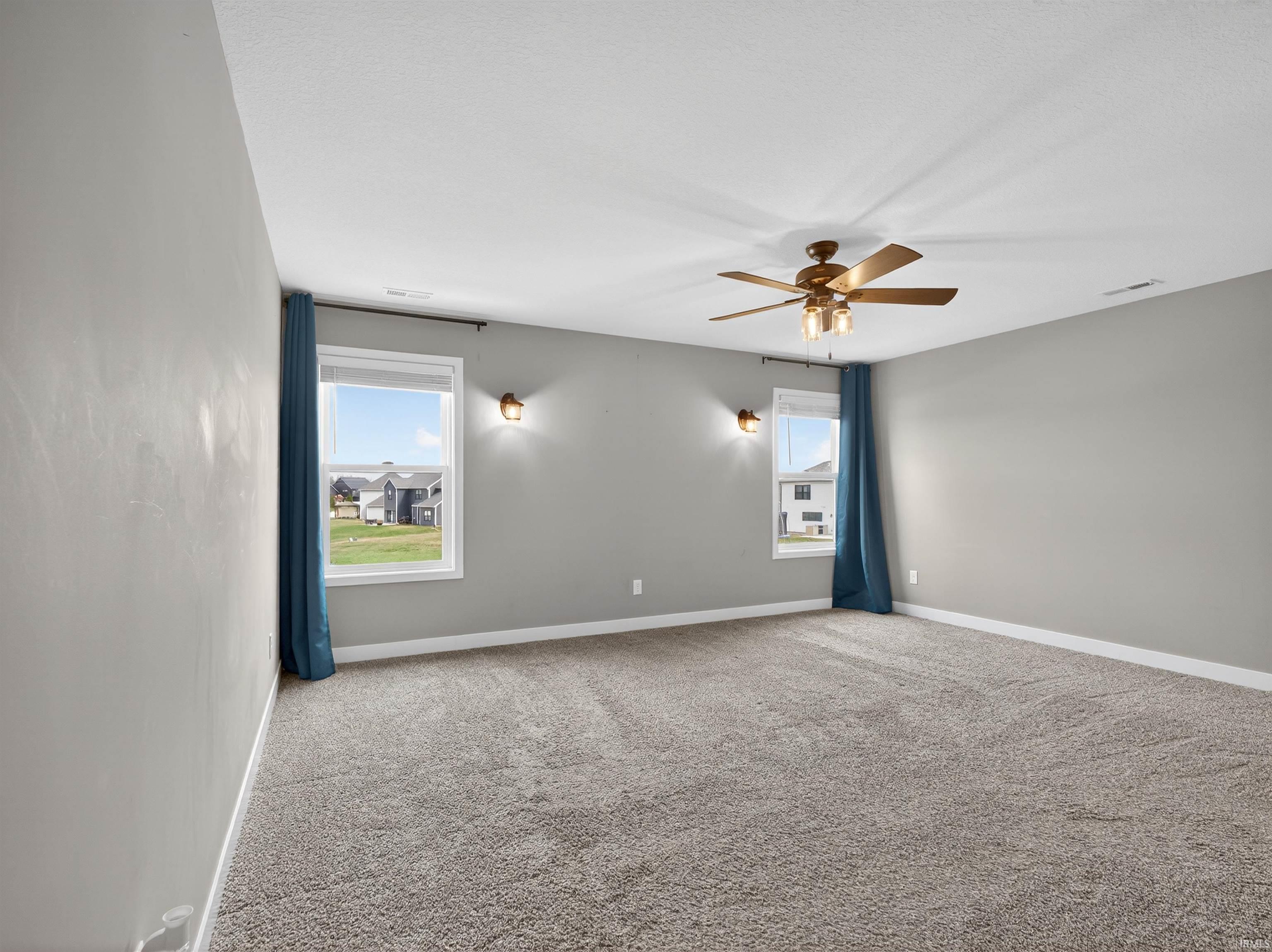 Carpeted spare room with plenty of natural light and a ceiling fan