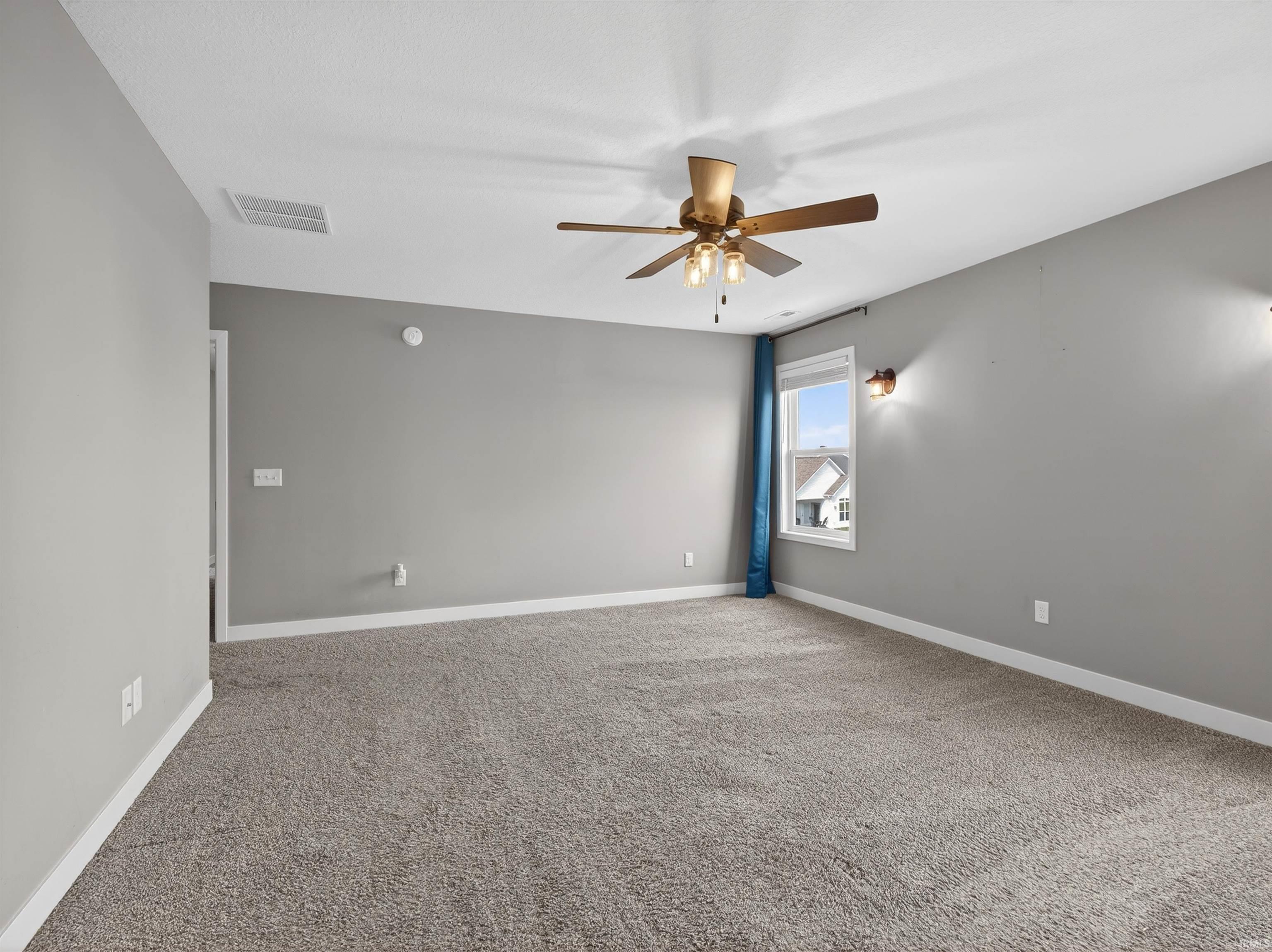 Carpeted empty room with ceiling fan and baseboards