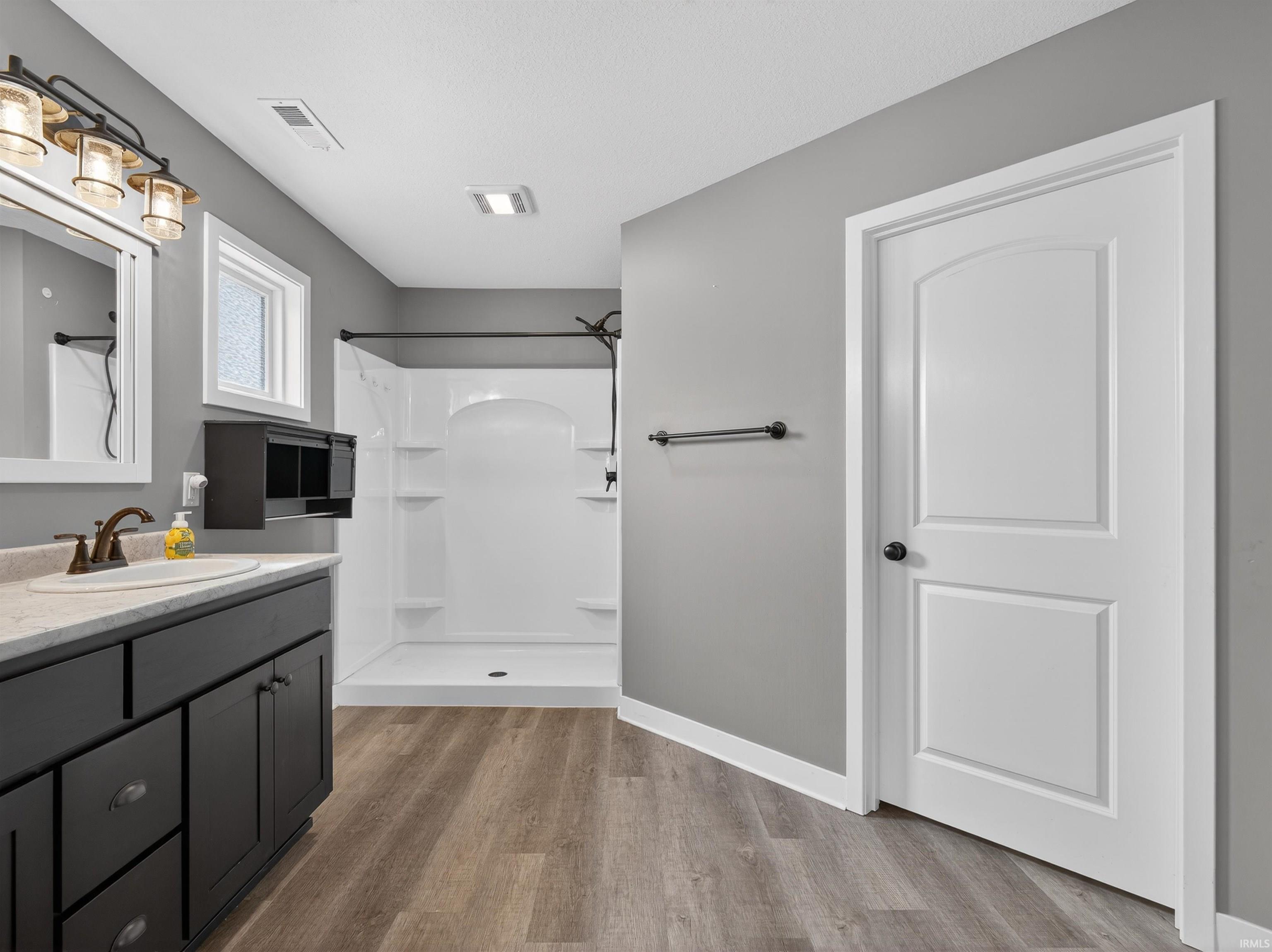 Bathroom featuring a shower stall, vanity, and light wood-style flooring