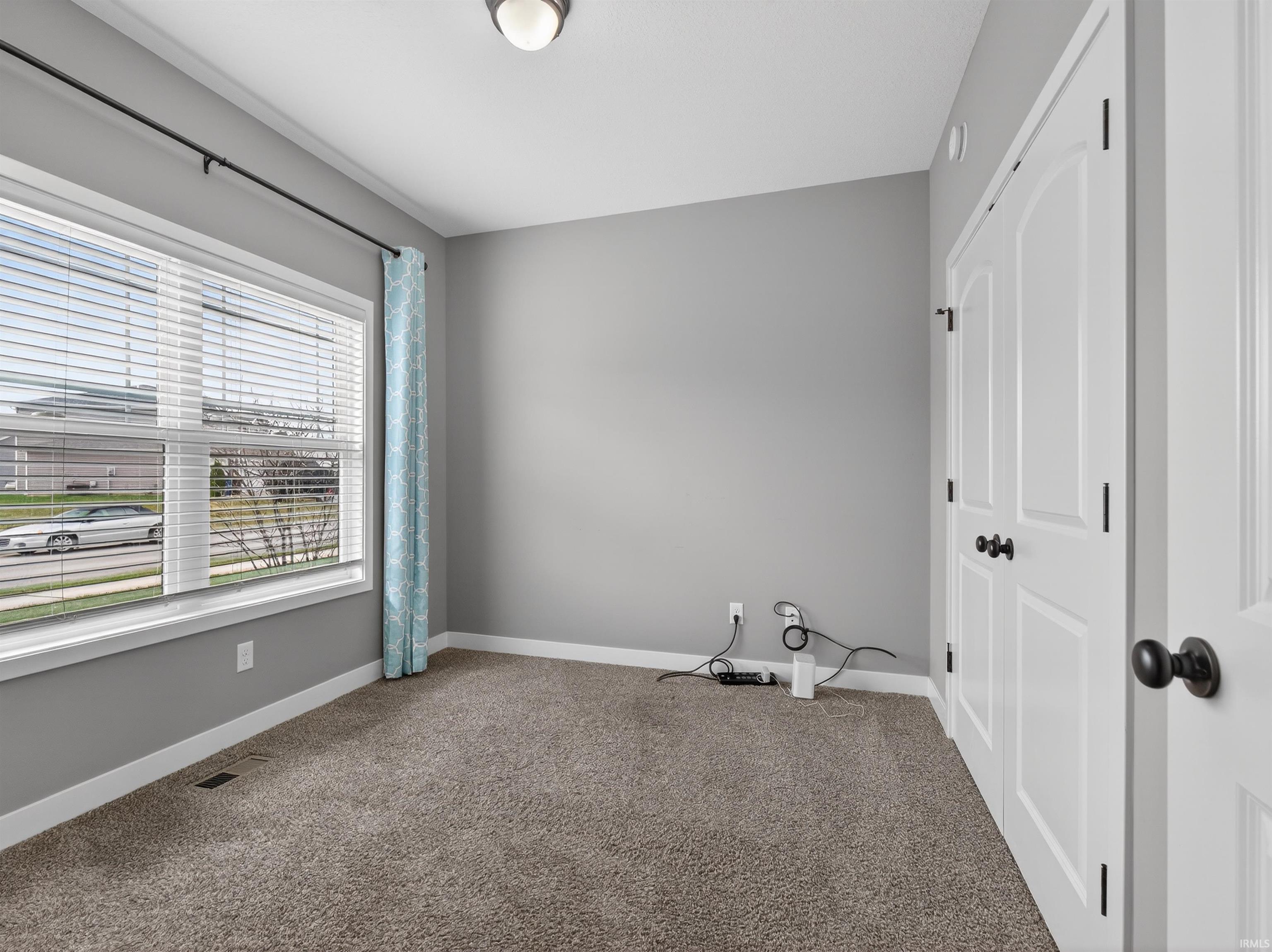 Spare room featuring carpet flooring and baseboards
