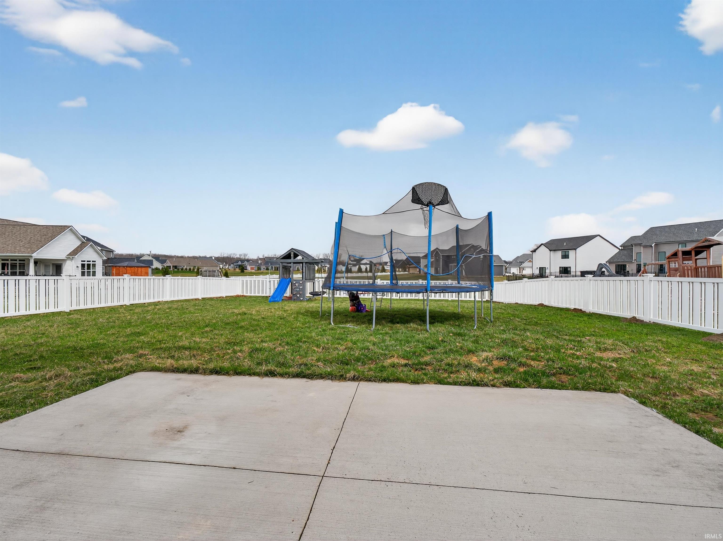 Fenced backyard with a residential view, a trampoline, and a playground