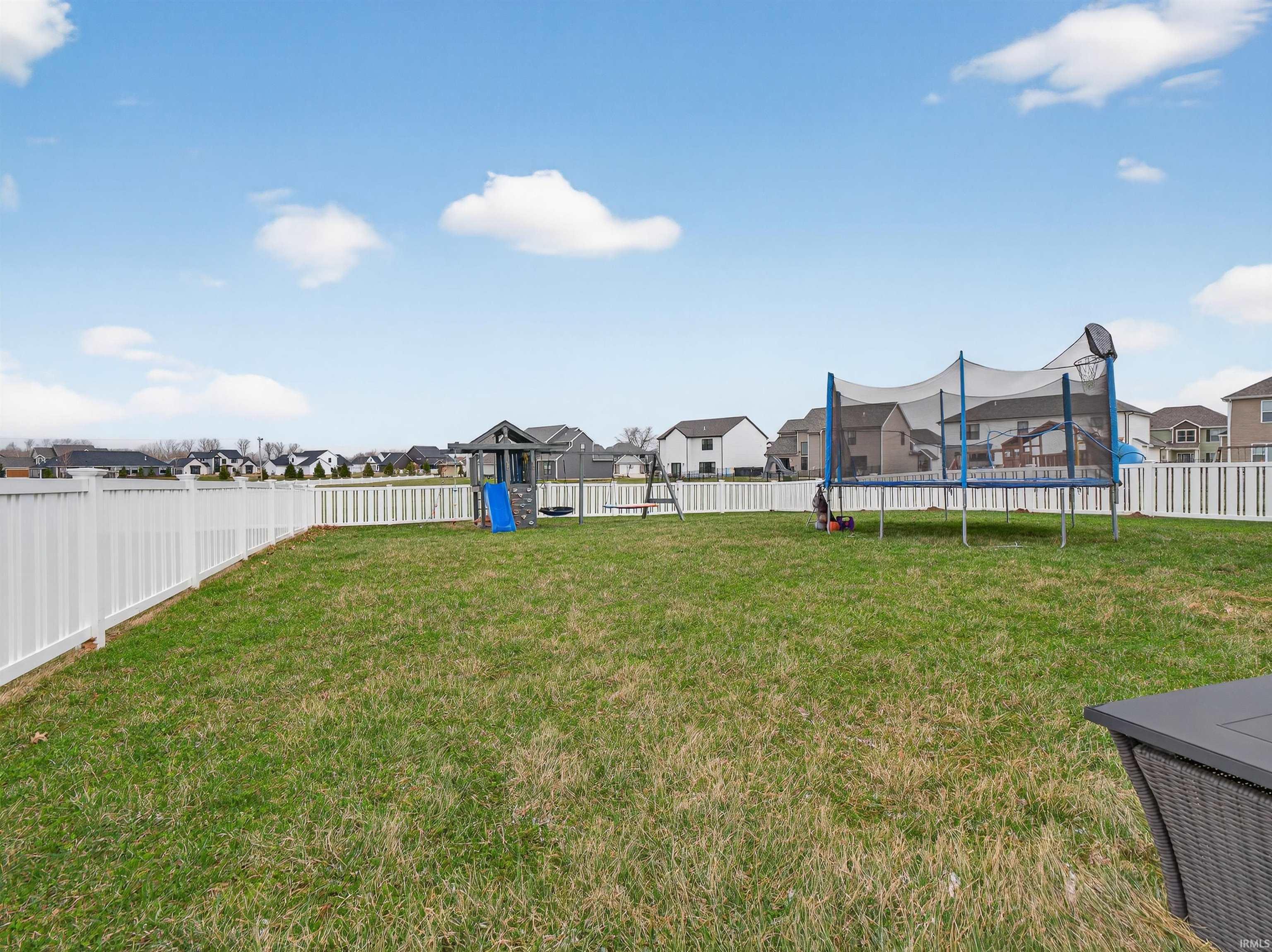 Fenced backyard with a residential view, a trampoline, and a playground