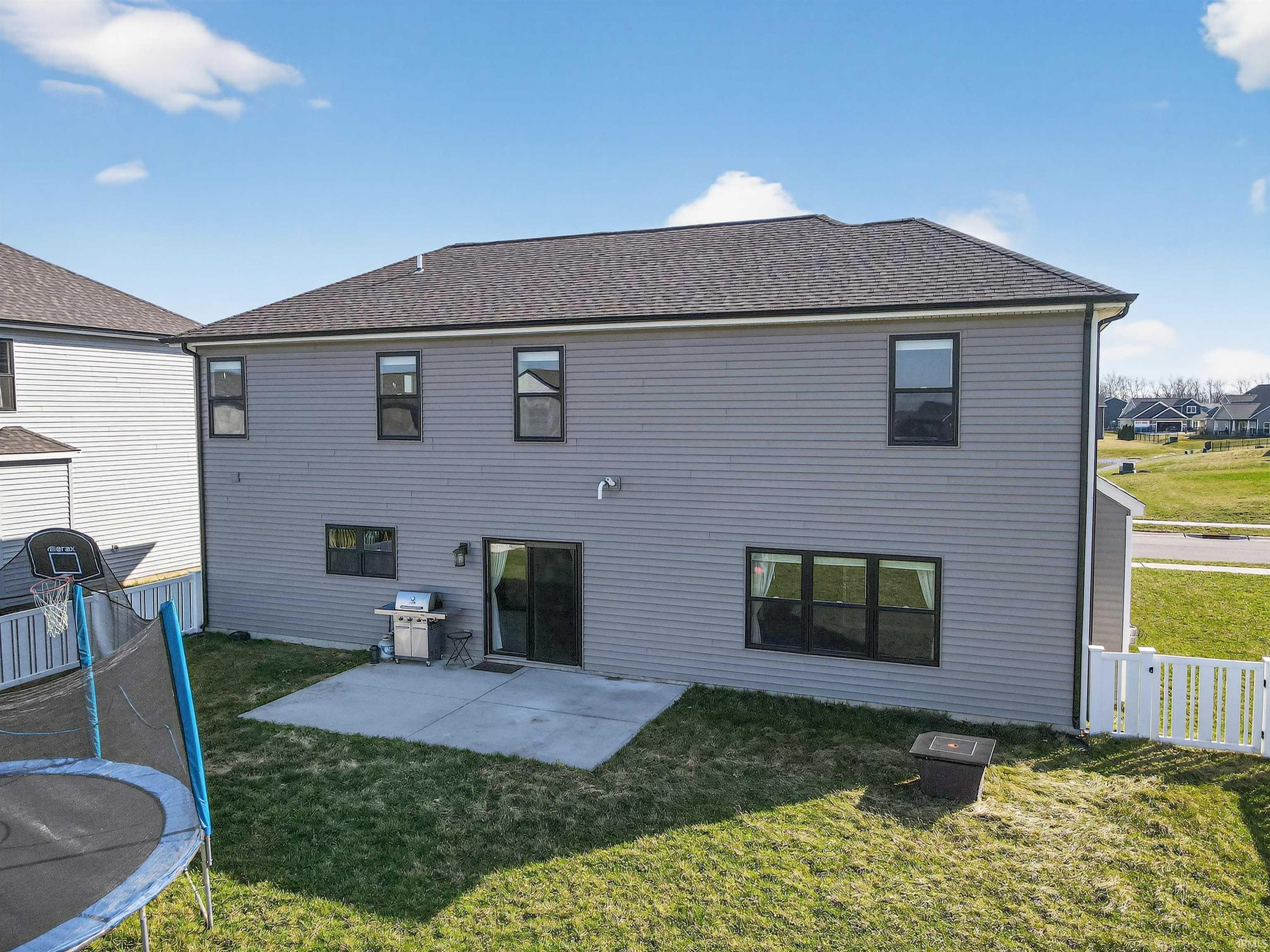 Back of house with a patio, a shingled roof, and a trampoline