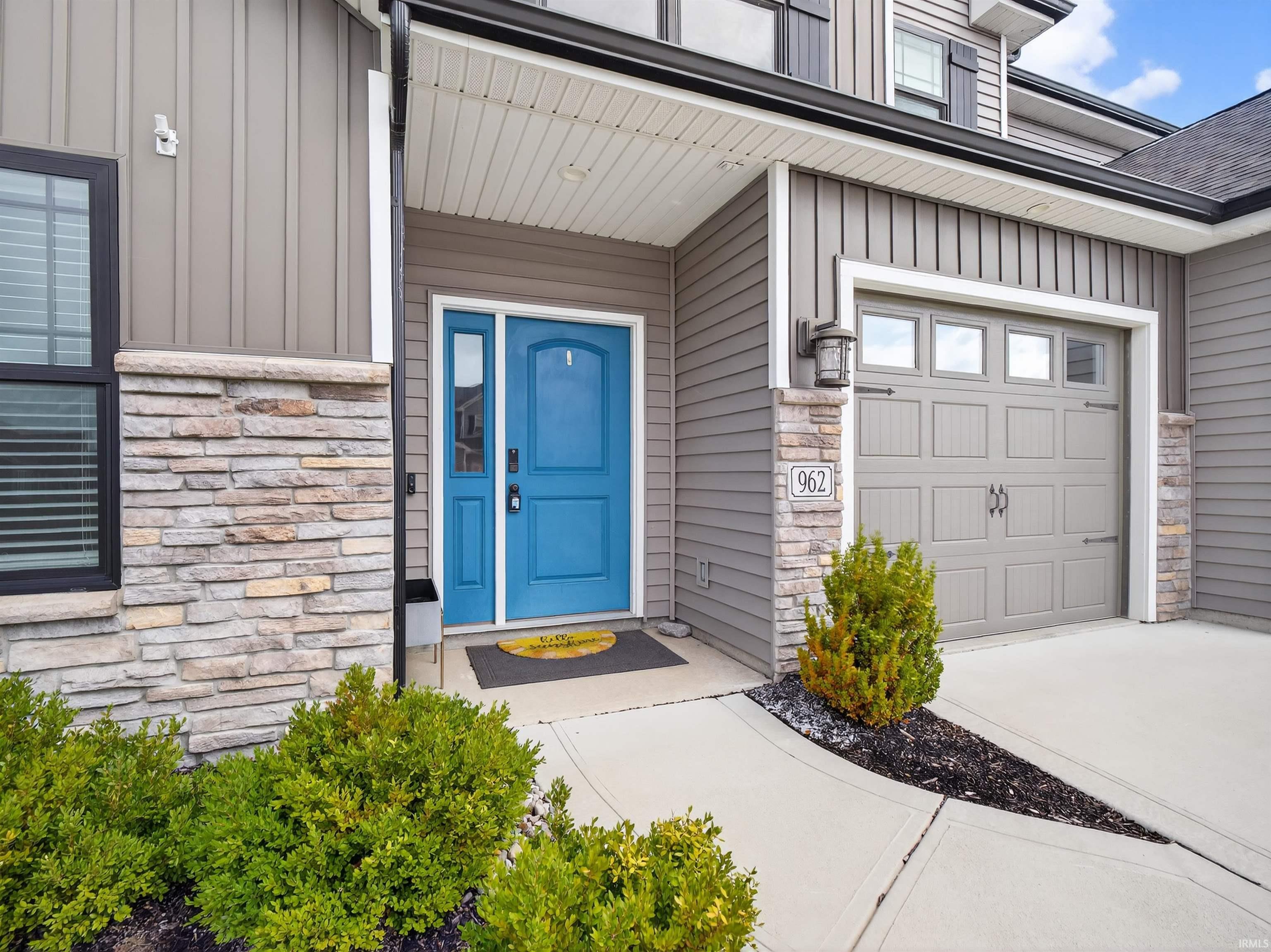Property entrance featuring stone siding, board and batten siding, and driveway