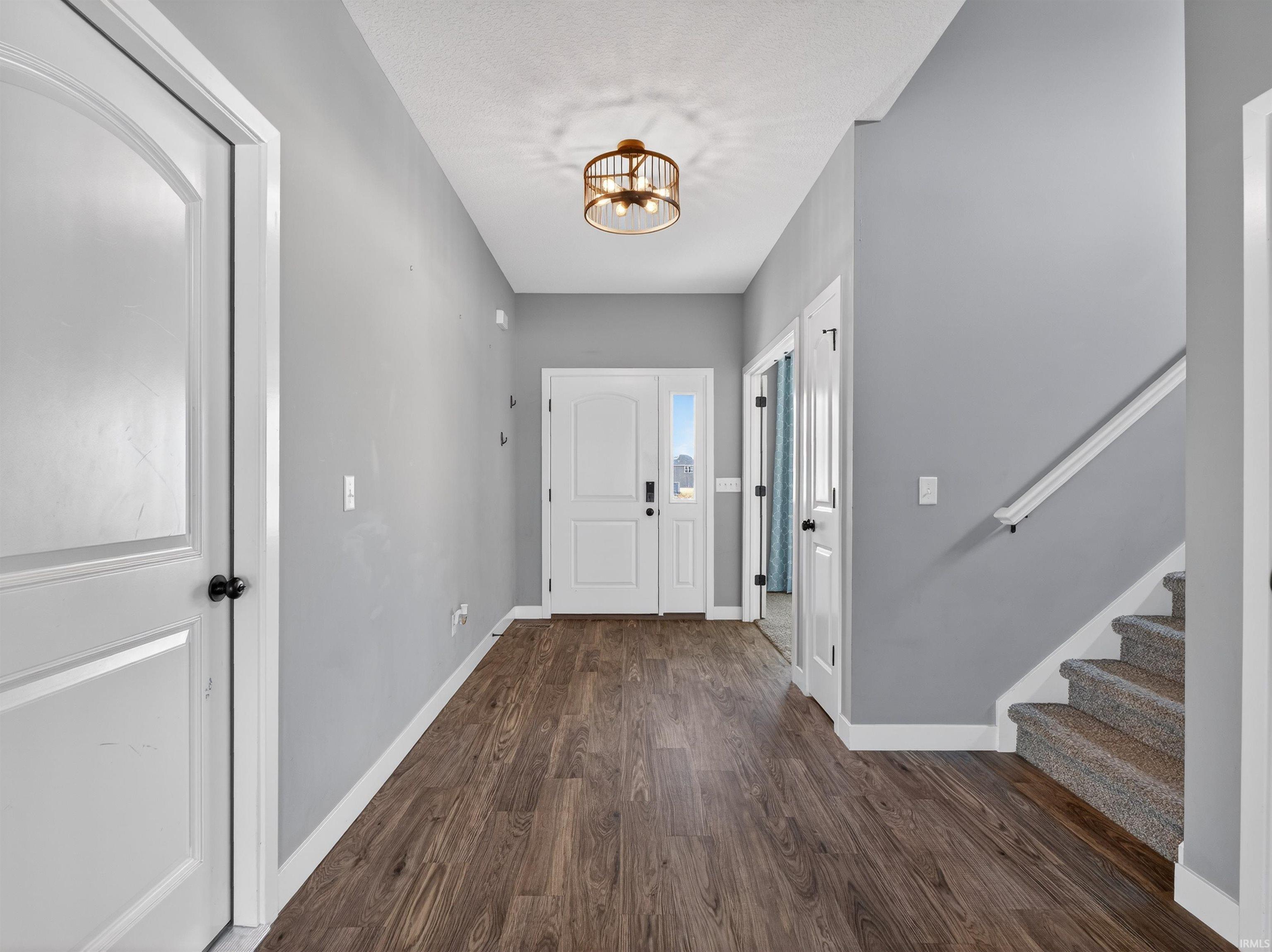 Entrance foyer featuring dark wood-type flooring, suspended lighting, and a textured ceiling