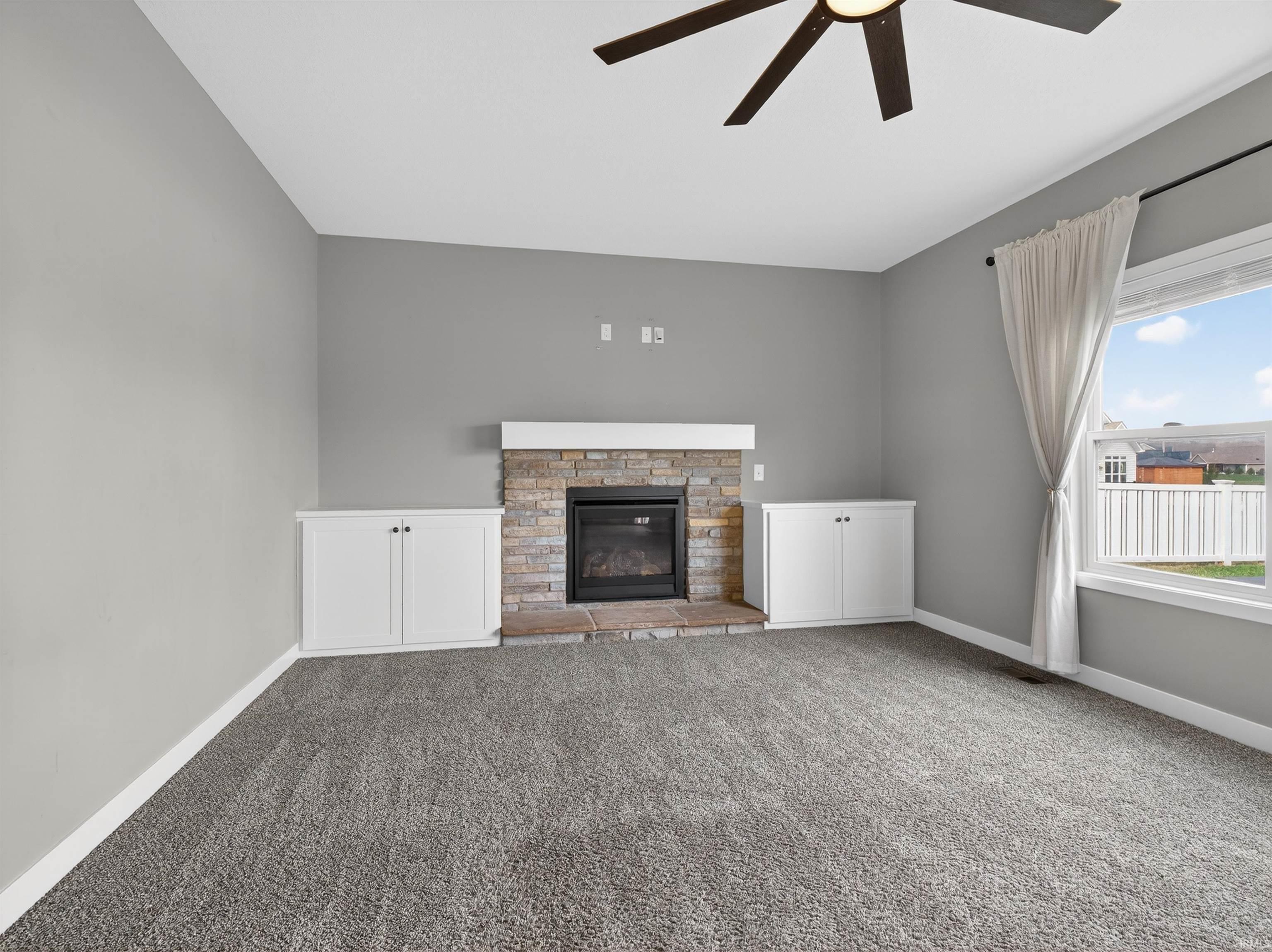 Unfurnished living room with a ceiling fan, a glass covered fireplace, and carpet floors