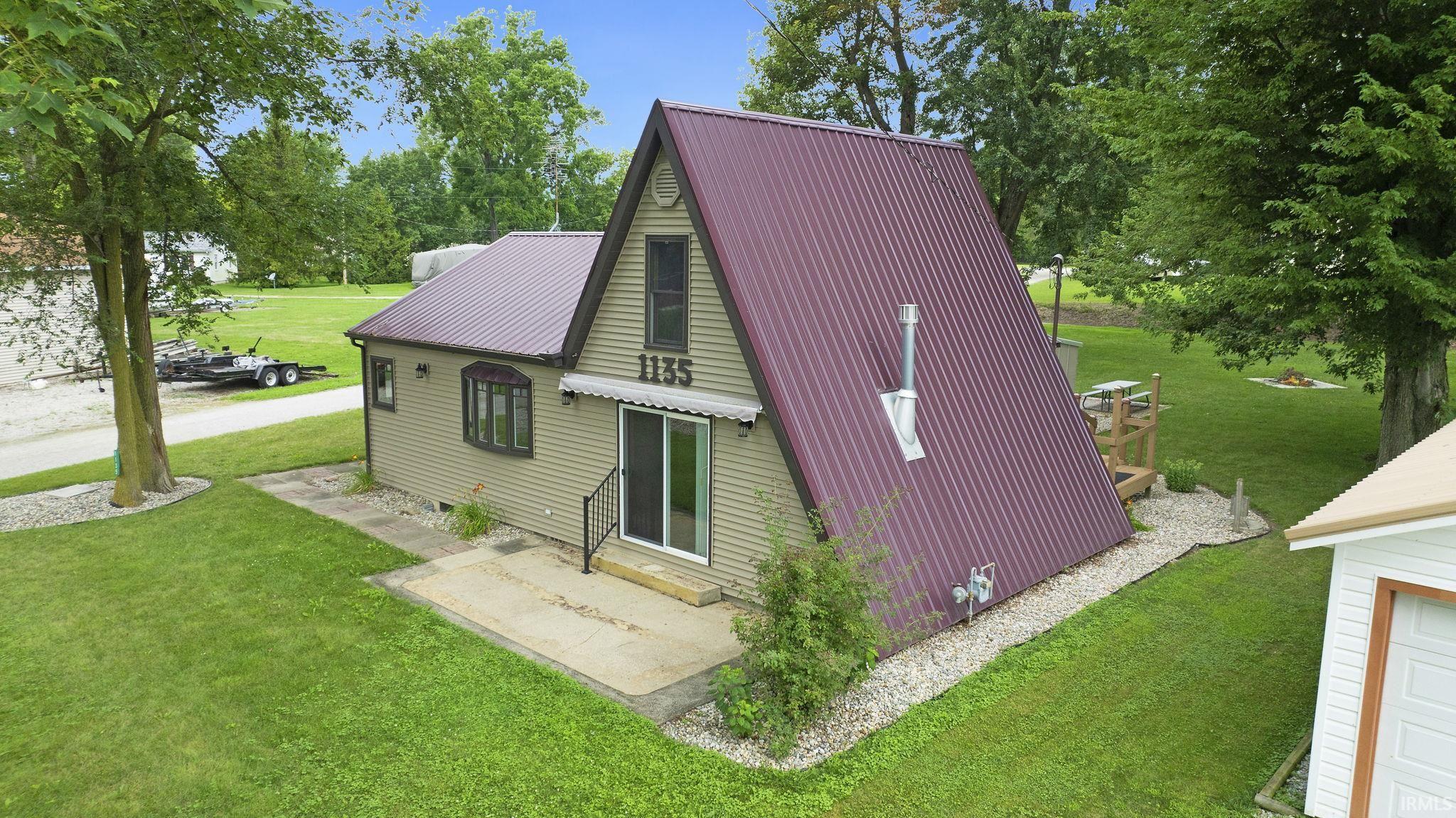 View of side of home featuring a lawn and a metal roof