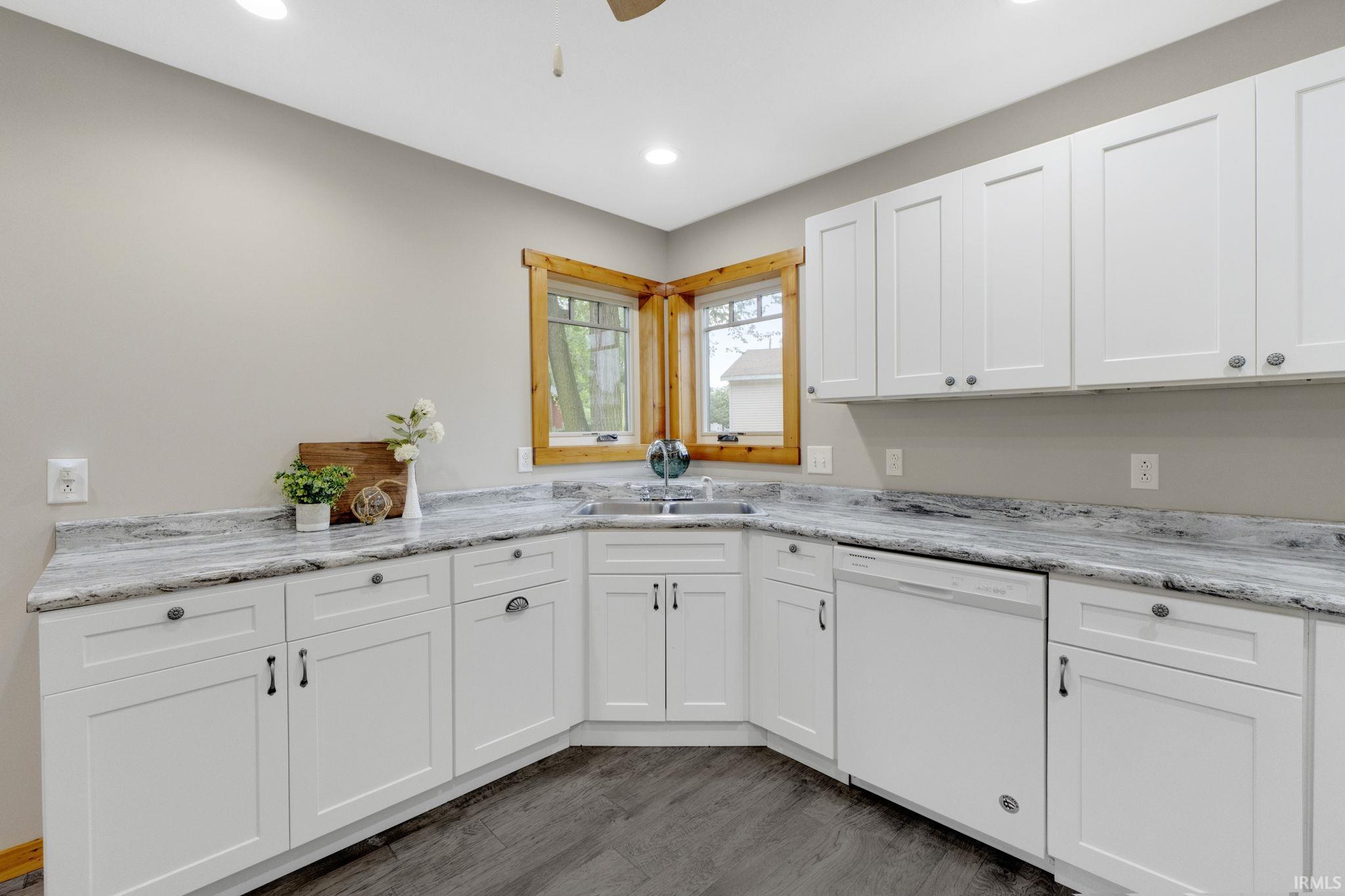 Kitchen with white cabinetry, dishwasher, dark wood finished floors, light stone counters, and recessed lighting
