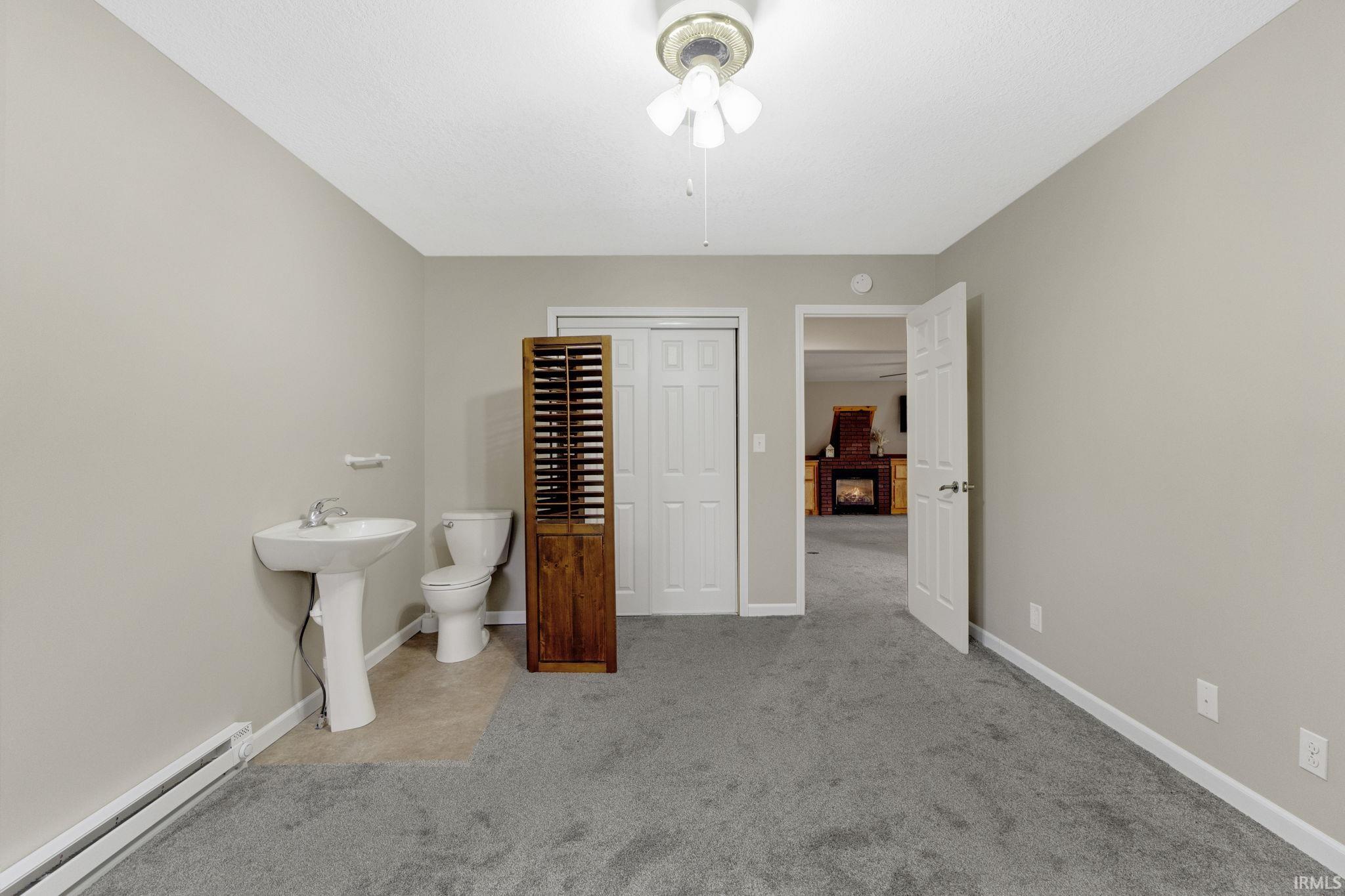 Bathroom with a baseboard heating unit and light carpet