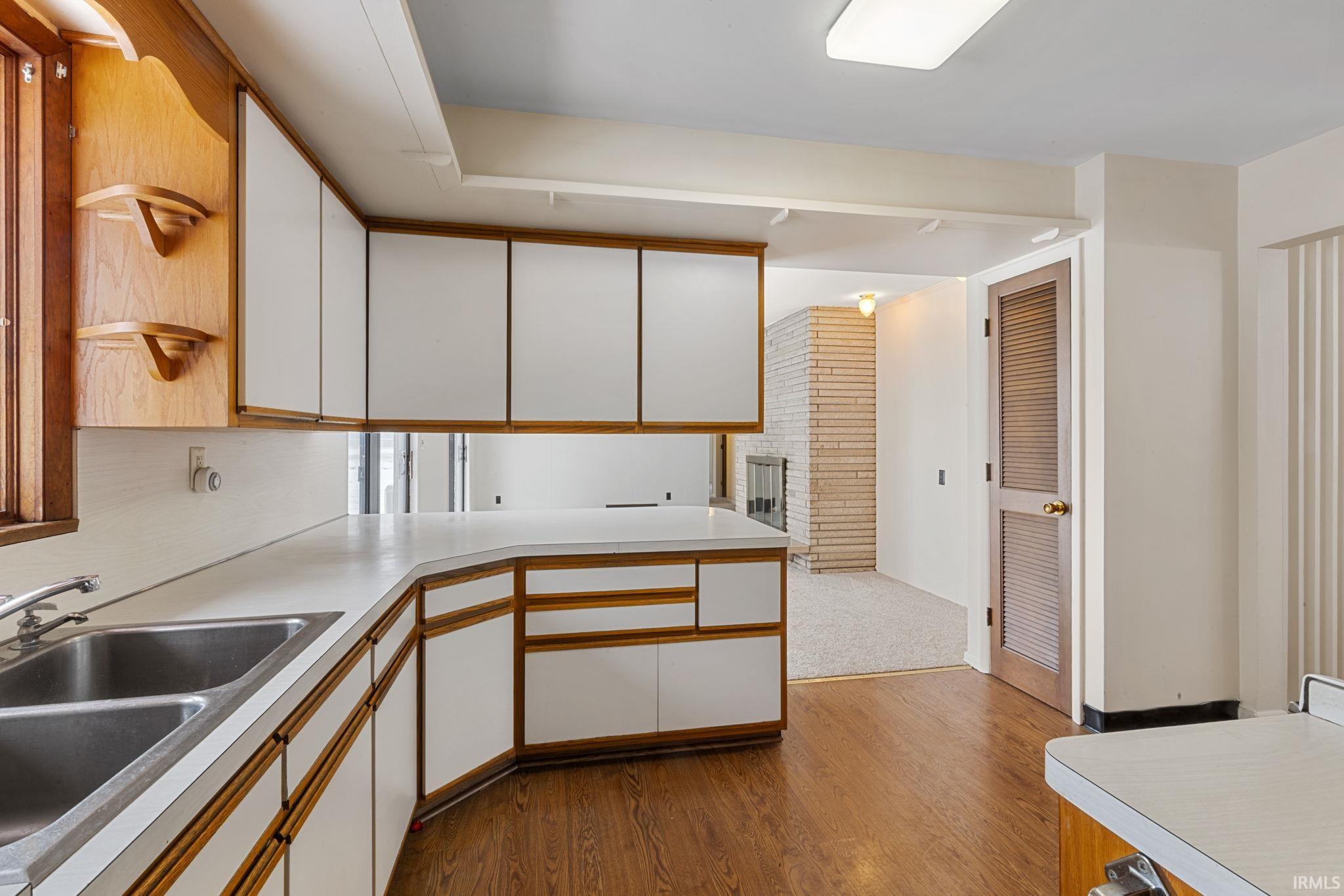 Two tone kitchen featuring two tone cabinets, dark wood-style flooring, and light countertops