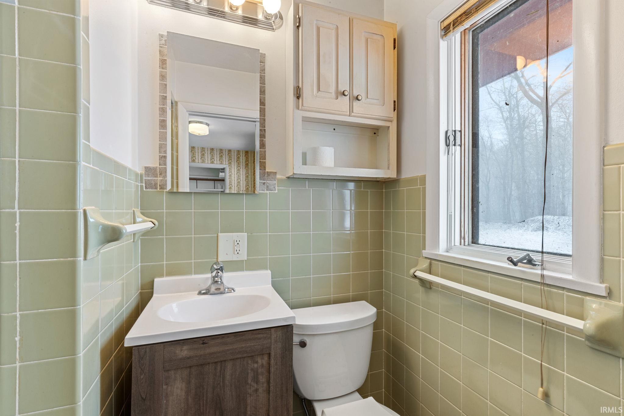 Half bathroom with vanity and tile walls