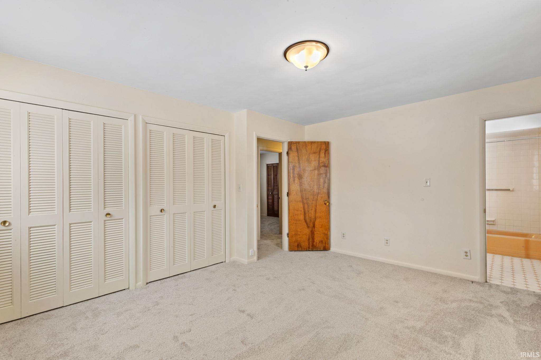 Unfurnished bedroom with multiple closets and carpet