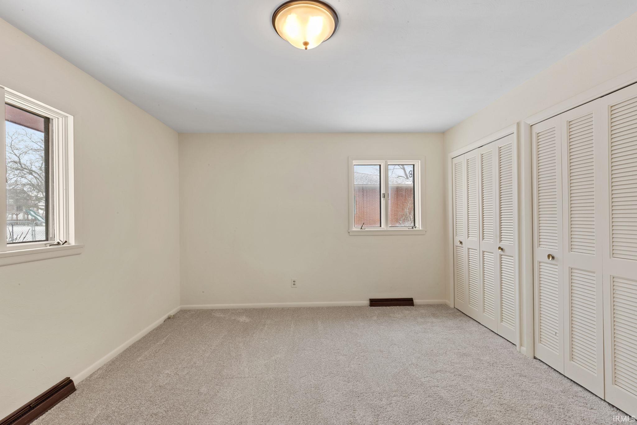 Unfurnished bedroom with multiple closets and carpet flooring
