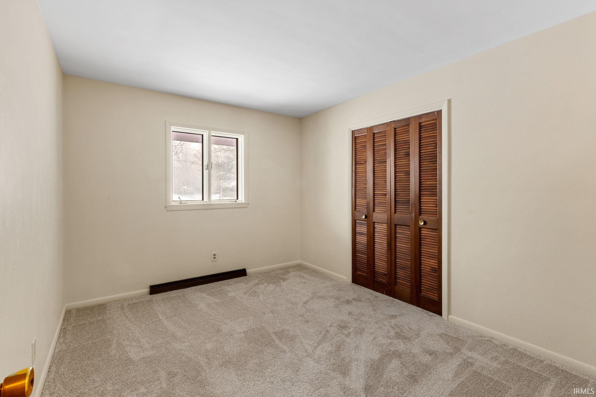 Unfurnished bedroom featuring light carpet and a closet