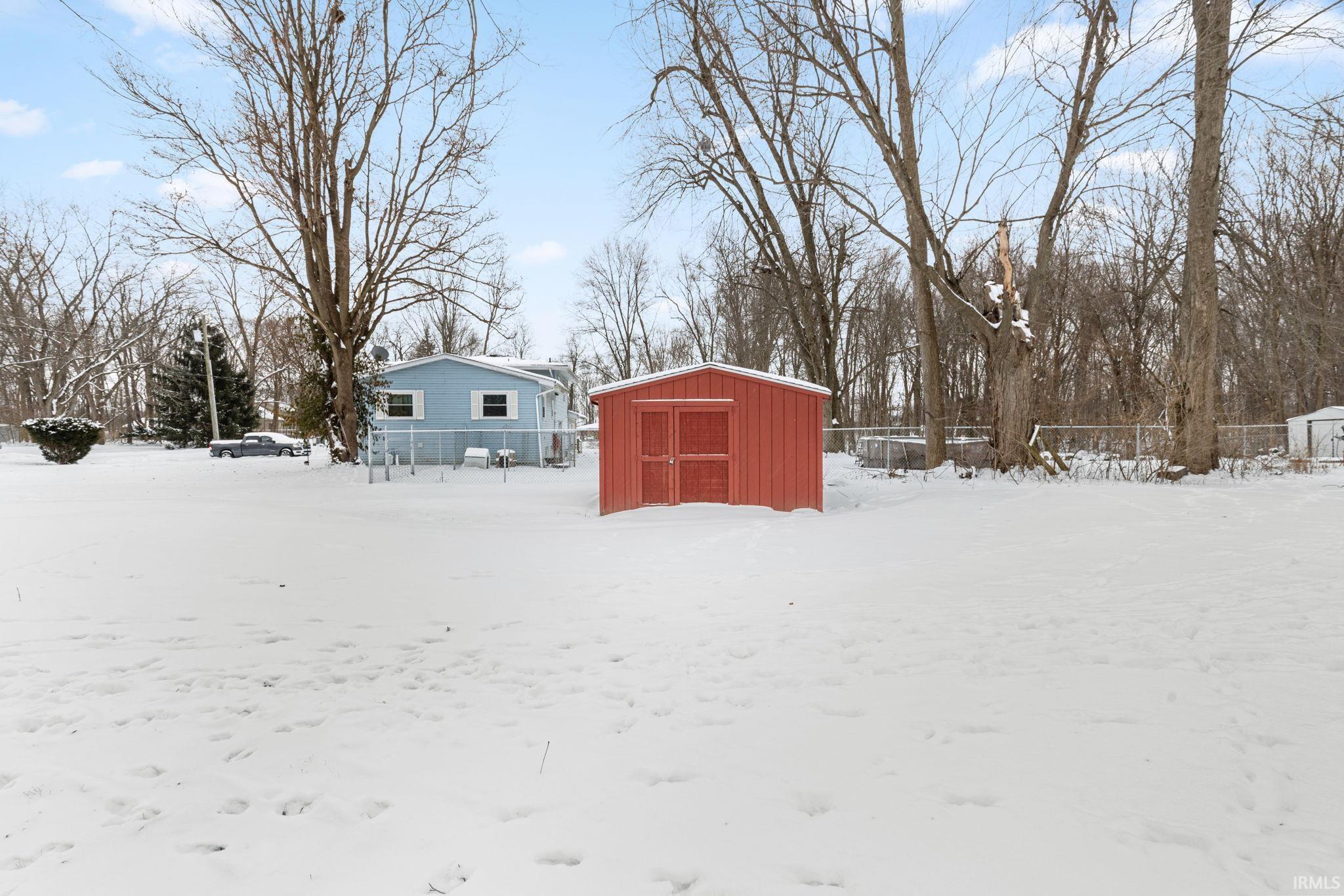Yard layered in snow with a storage unit