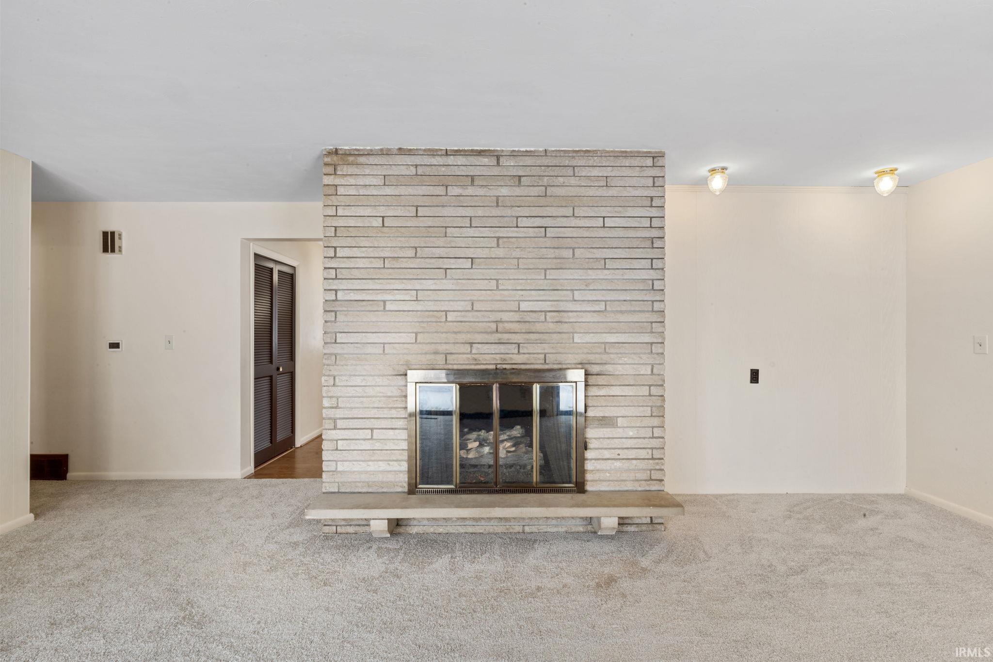 Unfurnished living room with carpet and a fireplace