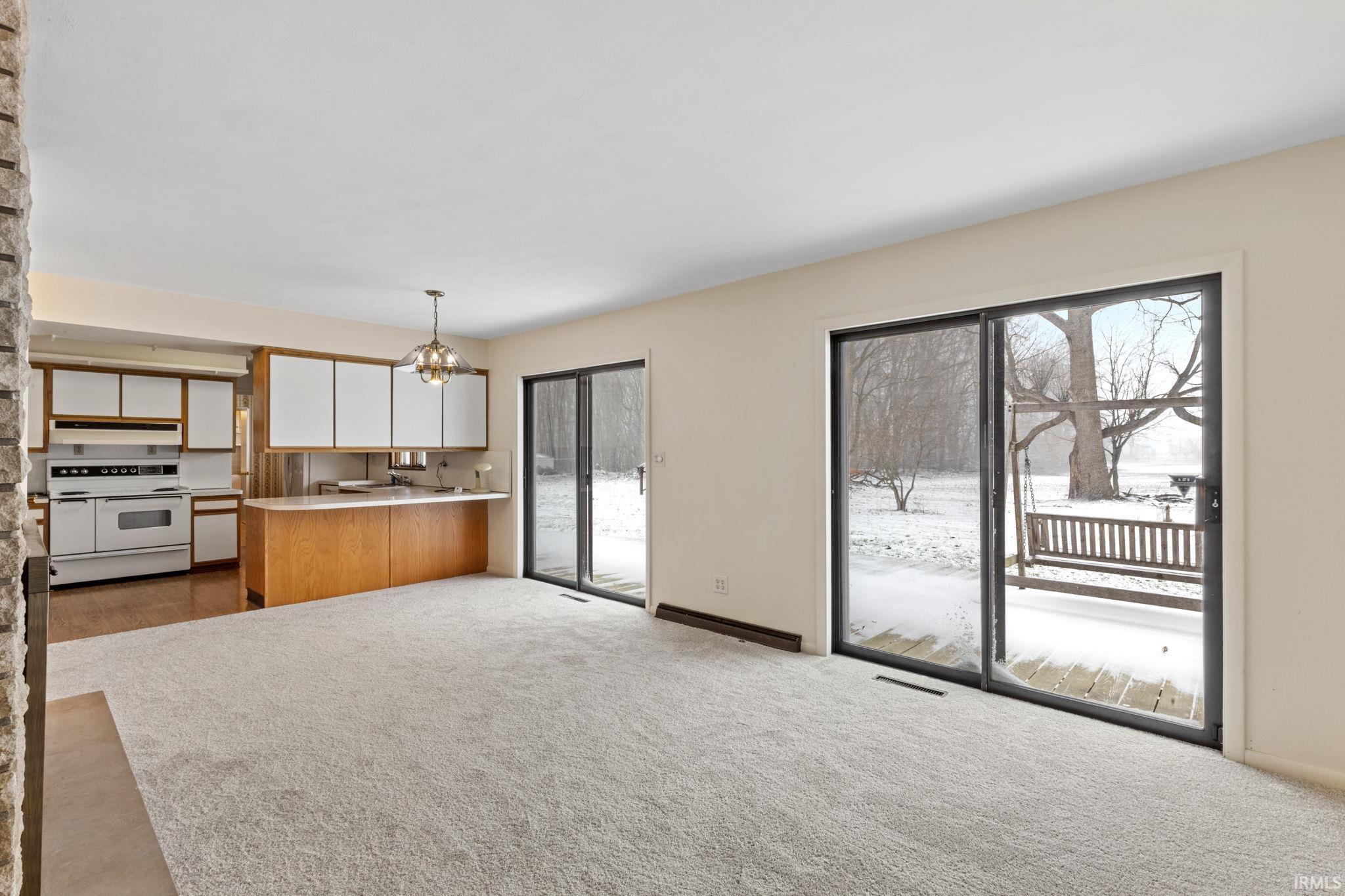 Two tone kitchen with dual tone cabinets, light countertops, double oven range, light carpet, and suspended lighting