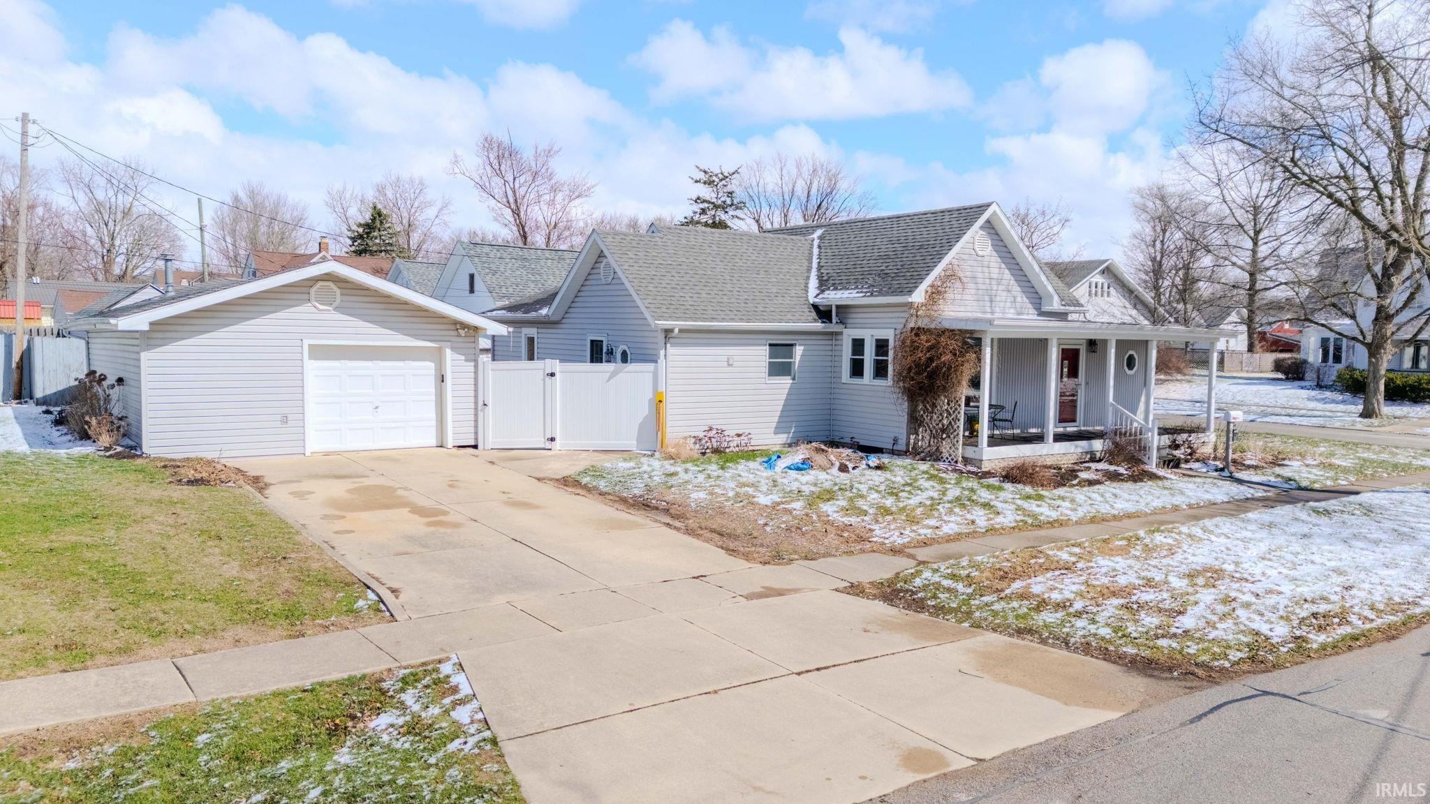 View of front of house featuring a gate, concrete driveway, a porch, a detached garage, and a shingled roof
