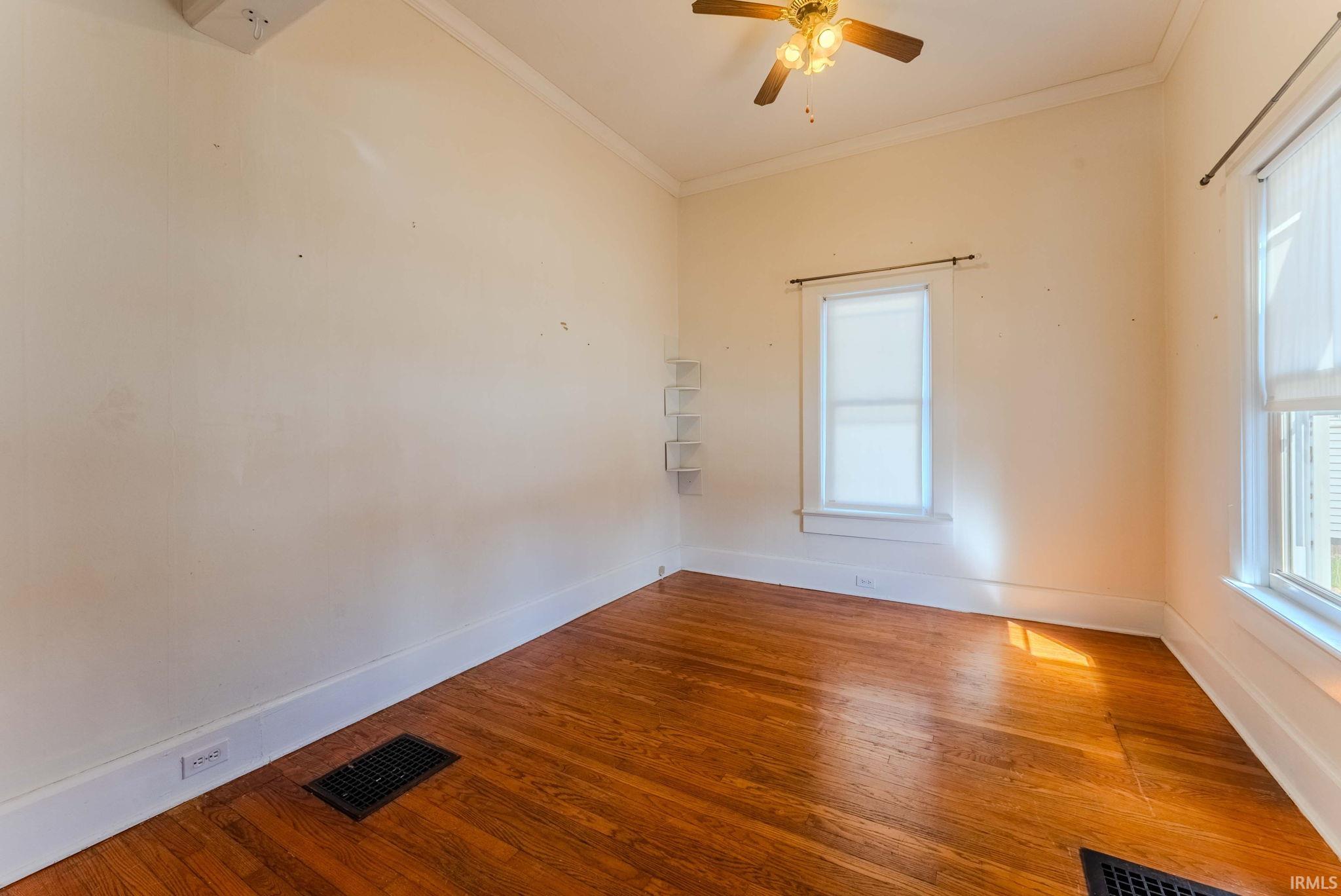 Empty room with hardwood / wood-style flooring, ornamental molding, and a ceiling fan