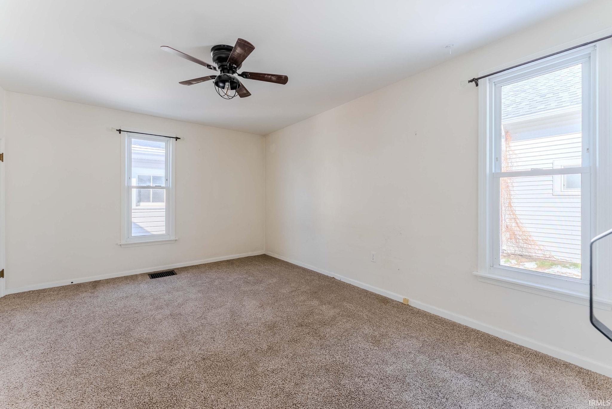 Carpeted spare room featuring baseboards and a ceiling fan