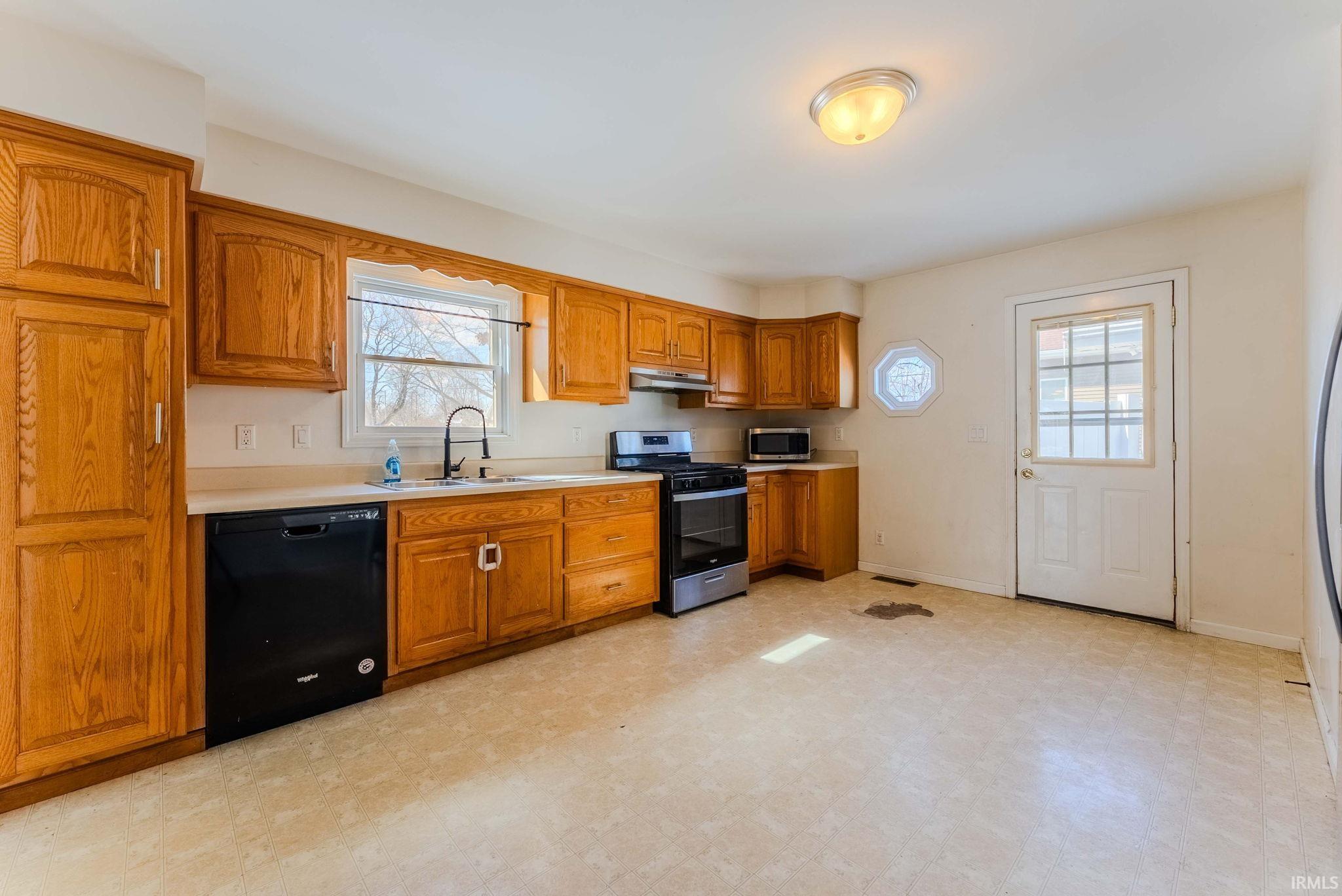 Kitchen with light floors, stainless steel appliances, wood finish cabinetry, and light countertops